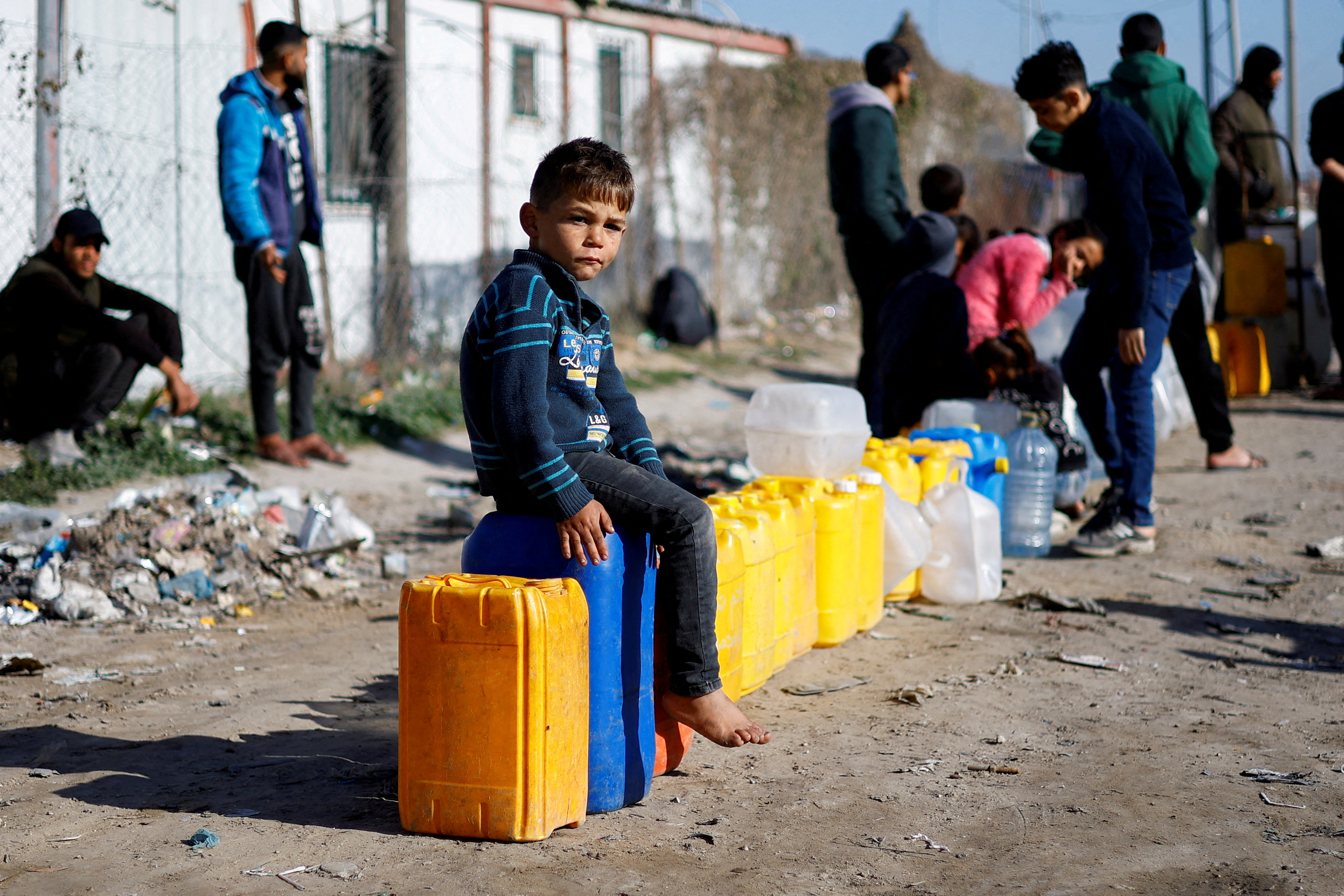 A displaced Palestinian boy, who fled his house due to Israeli strikes, sits on a water canister at a tent camp in Rafah./Reuters/Ibraheem Abu Mustafa.
