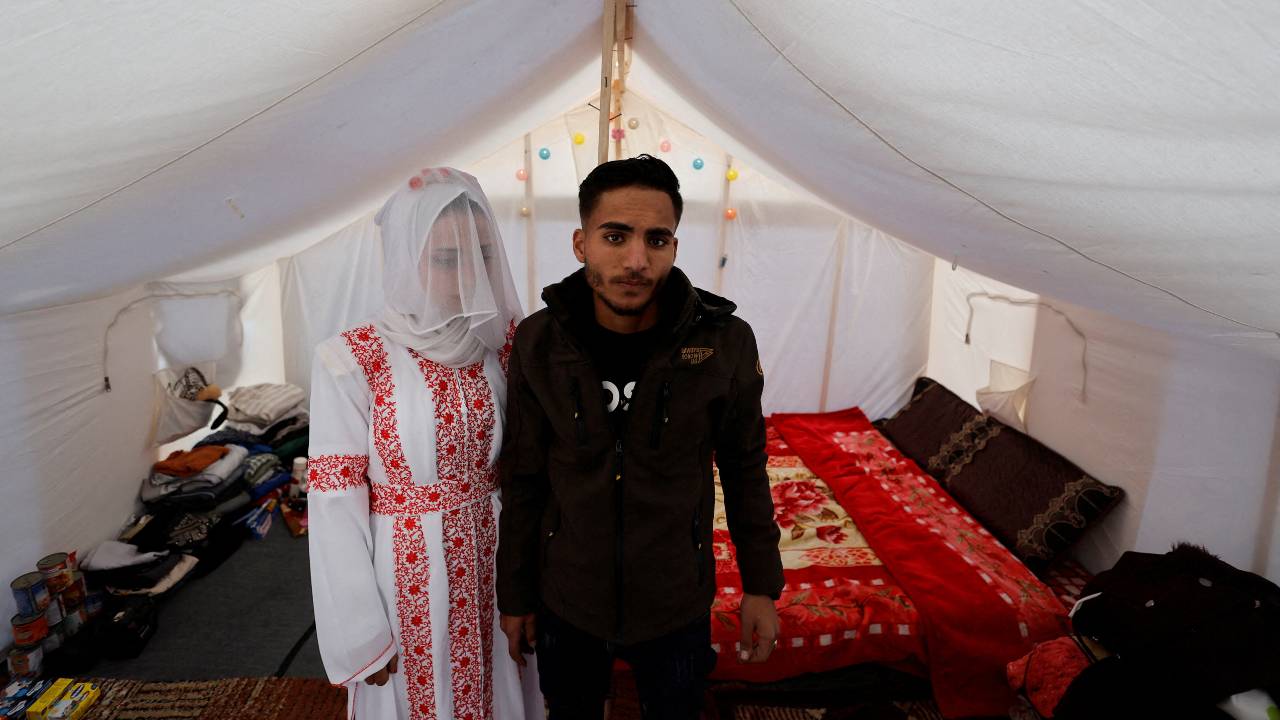 A Palestinian couple, Mohammed Al-Ghandour and his bride Shahad, stands in a tent camp in Rafah for their wedding. /Mohammed Salem/Reuters