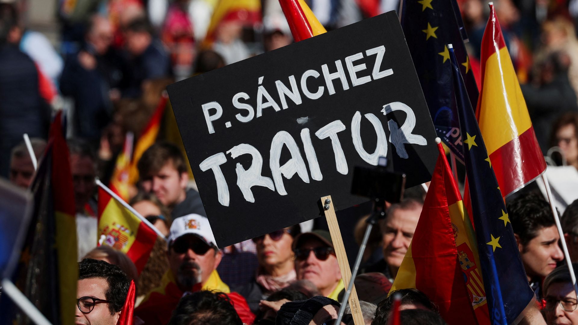 A protester holds a placard that calls Pedro Sanchez a 'traitor' during a demonstration in Madrid, Spain on Sunday. /Isabel Infantes/Reuters