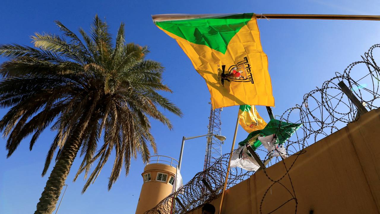 The flag of the Kataib Hezbollah militia group appears during a protest against air strikes on their bases, outside the U.S. Embassy in Baghdad. /Thaier al-Sudani/Reuters