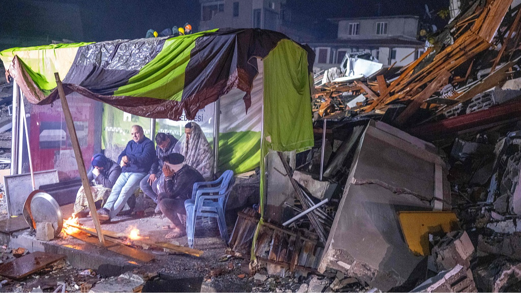 People take shelter at a bus stop in the immediate aftermath of the earthquakes. /Bulent Kilic/AFP