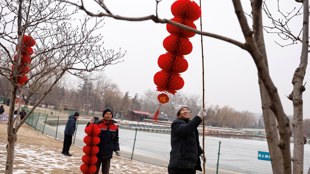 A worker puts up a lantern decoration on a tree, ahead of the Chinese Lunar New Year, at a park in Beijing. /Tingshu Wang/Reuters