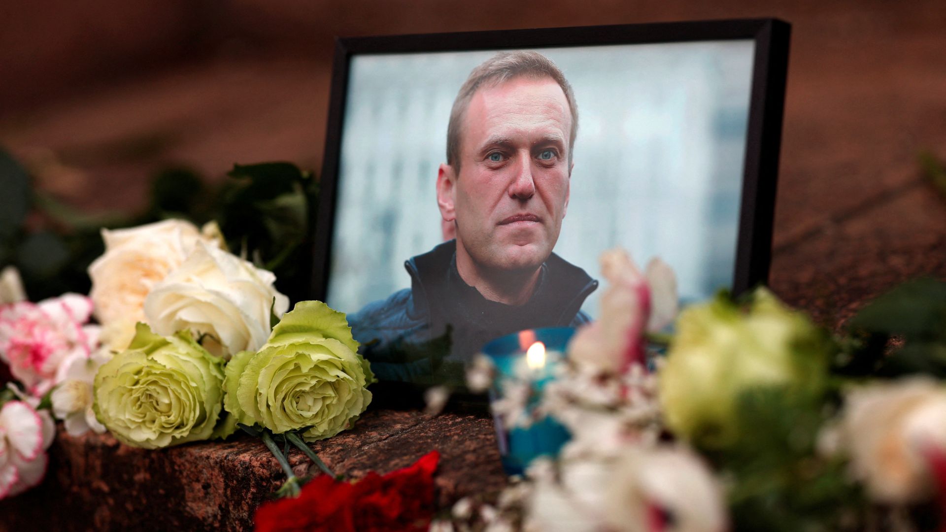 Flowers and a candle are placed next to a portrait of Navalny in Paris, France. /Gonzalo Fuentes/Reuters