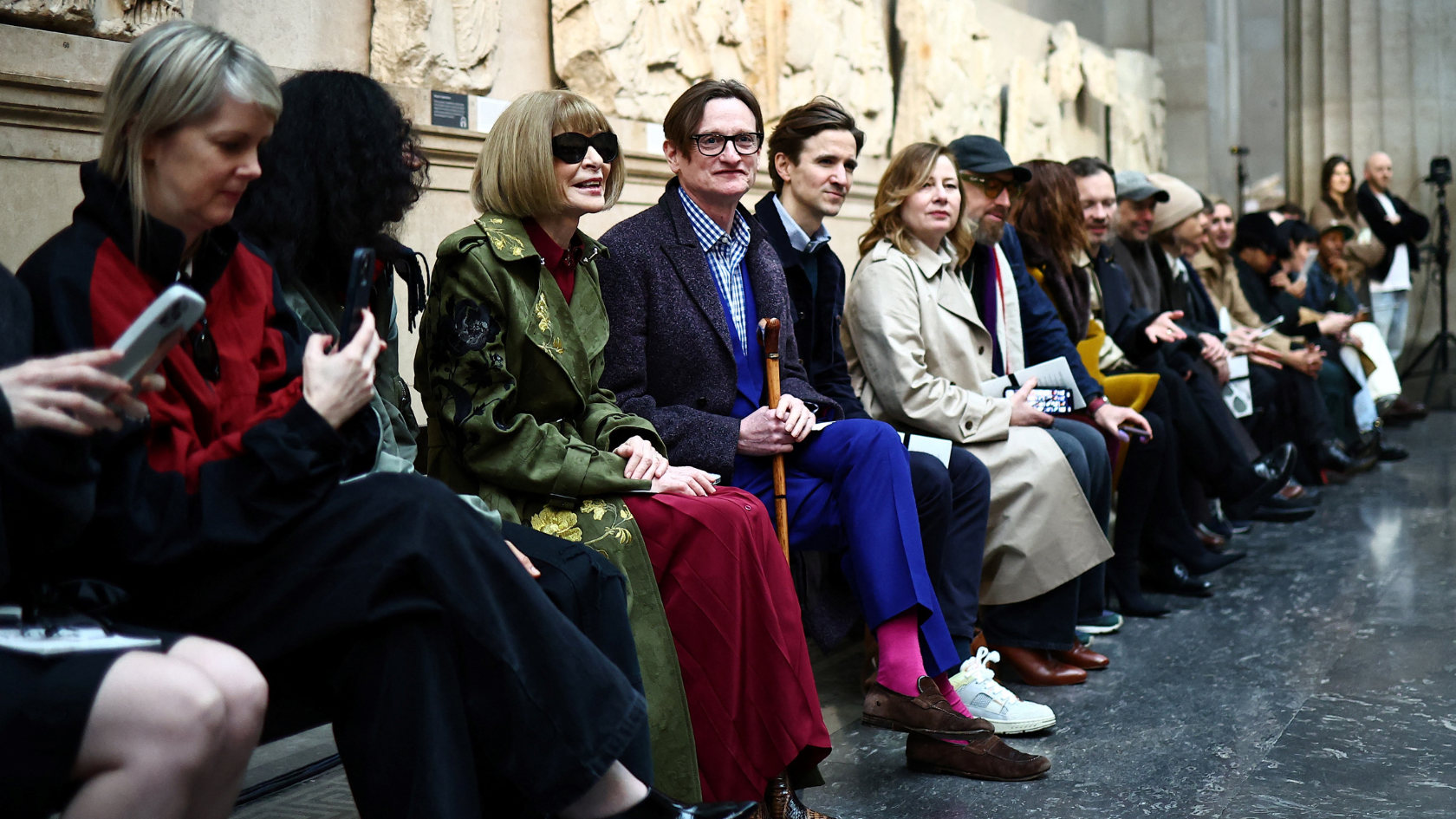 Vogue editor-in-chief Anna Wintour (dark glasses) sits in front of the Parthenon Marbles at the British Museum prior to the Erdem fashion show. /Henry Nicholls/AFP