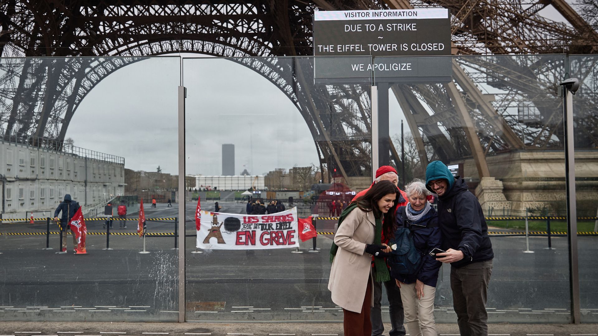 Pedestrians take a picture next to the Eiffel Tower, by a board informing visitors that the monument is closed. /Kiran Ridley/AFP
