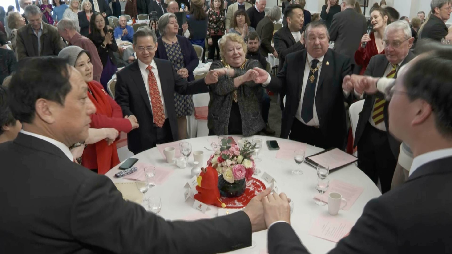 Chinese Ambassador to the UK Zheng Zeguang (red tie) takes part in a rendition of Auld Lang Syne at the Gloucester event. /CGTN