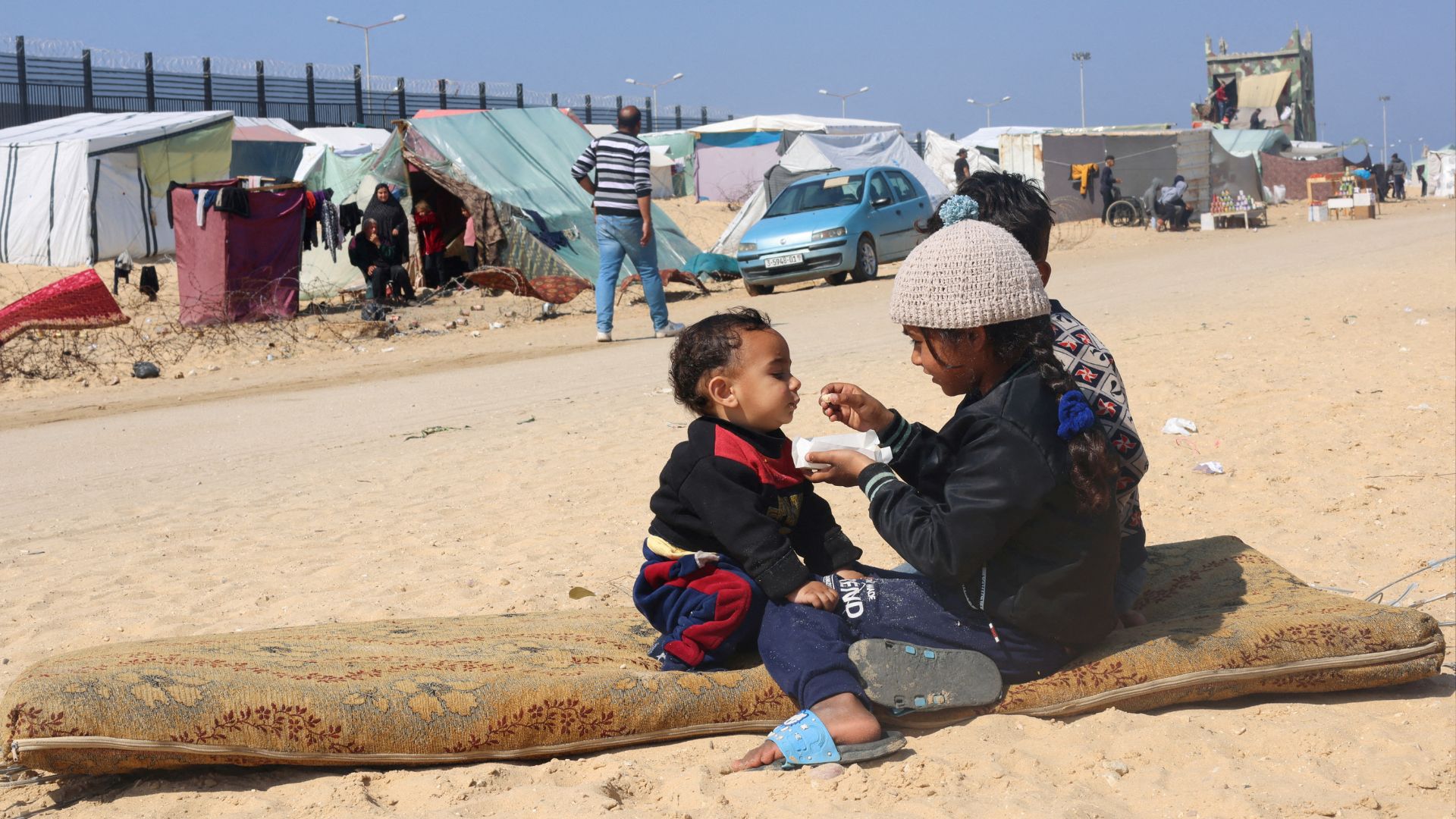 Displaced Palestinian girl, who fled her house due to Israeli strikes, feeds her brother at a tent camp, near the border with Egypt, in Rafah. /Saleh Salem/Reuters