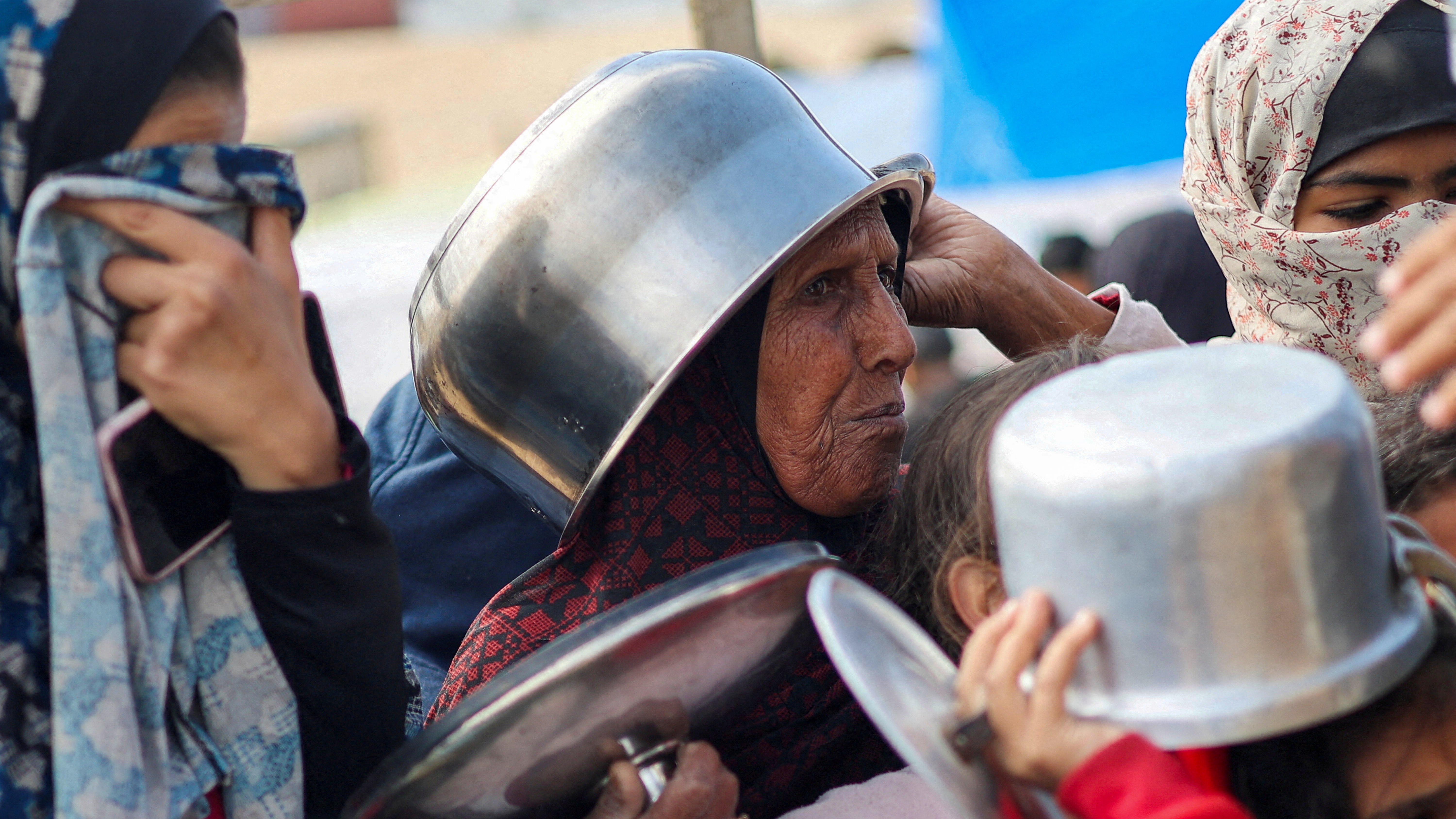 Gazan women and children using pots as protective headgear as they wait for aid Ibraheem. Abu Mustafa/Reuters