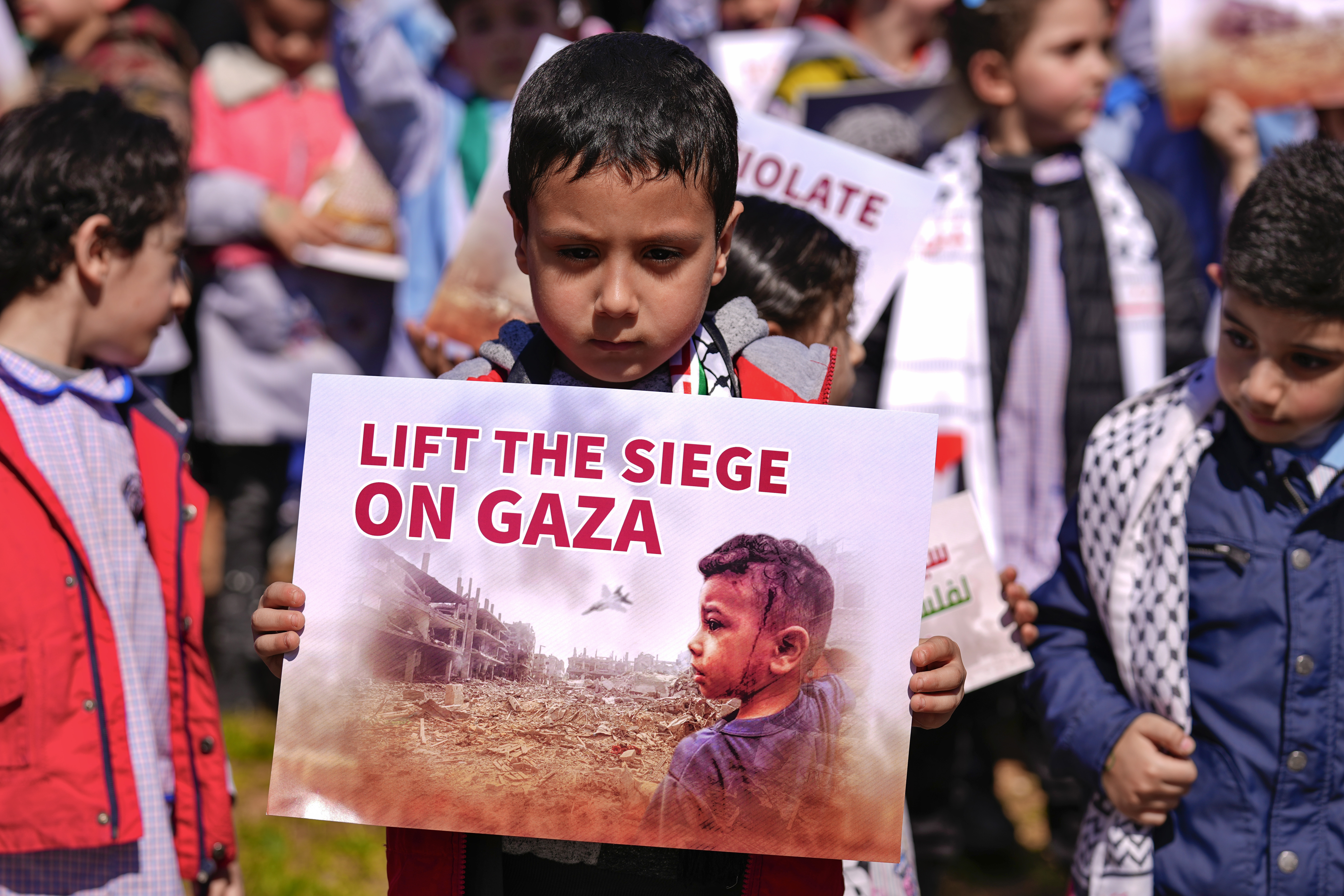 A Palestinian child living in Lebanon holds a placard during a protest to demand a ceasefire and support Palestinians in the Gaza Strip. /Bilal Hussein/AP 