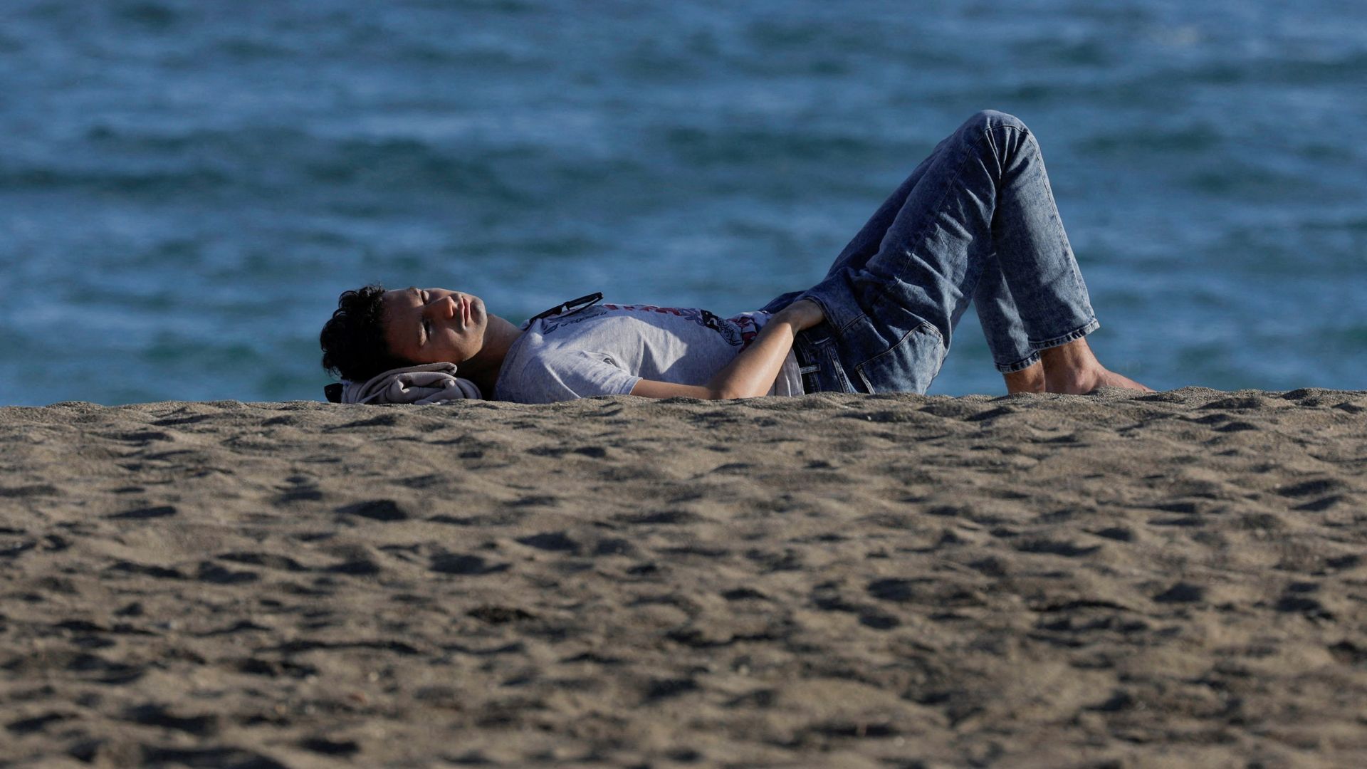 A man enjoys the sun in front of the sea during unseasonably warm temperatures in Malaga, southern Spain, on January 4. /Jon Nazca/Reuters