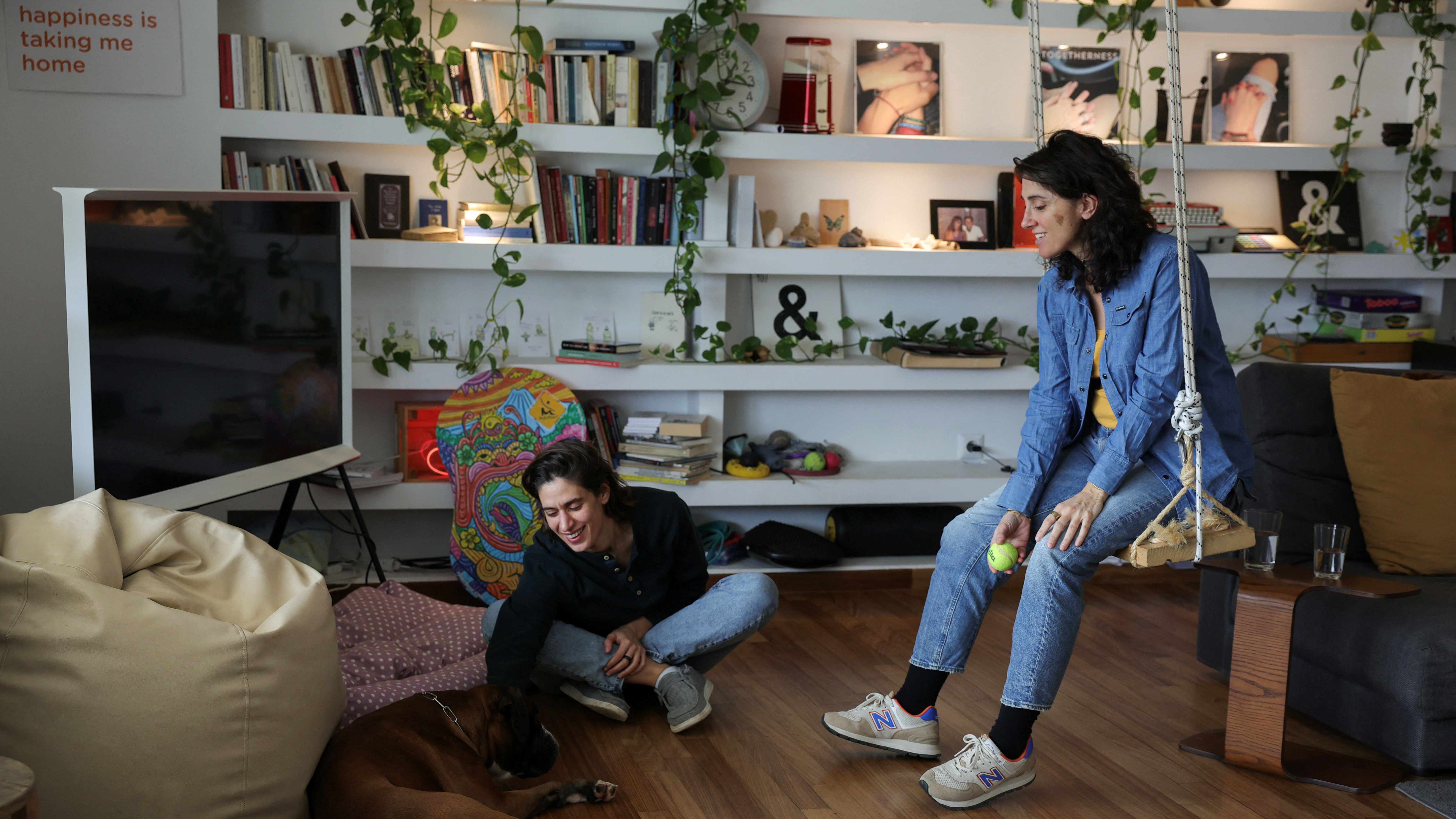 Danai Deligiorgi, 37, and Alexia Beziki, 43, with their dog in their apartment in Athens. /Louiza Vradi/Reuters