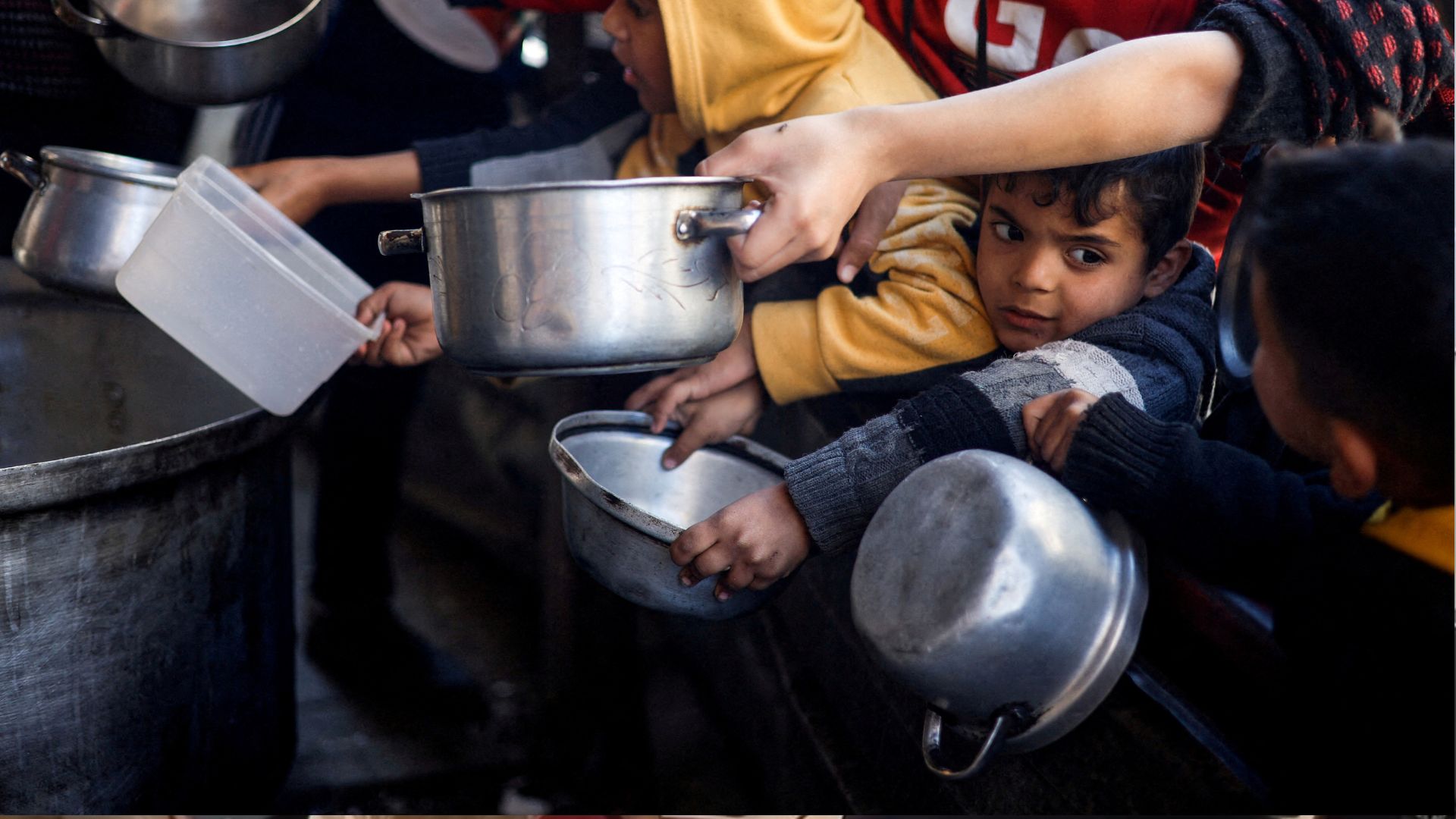 Palestinian children wait to receive food in Rafah. /Mohammed Salem/Reuters