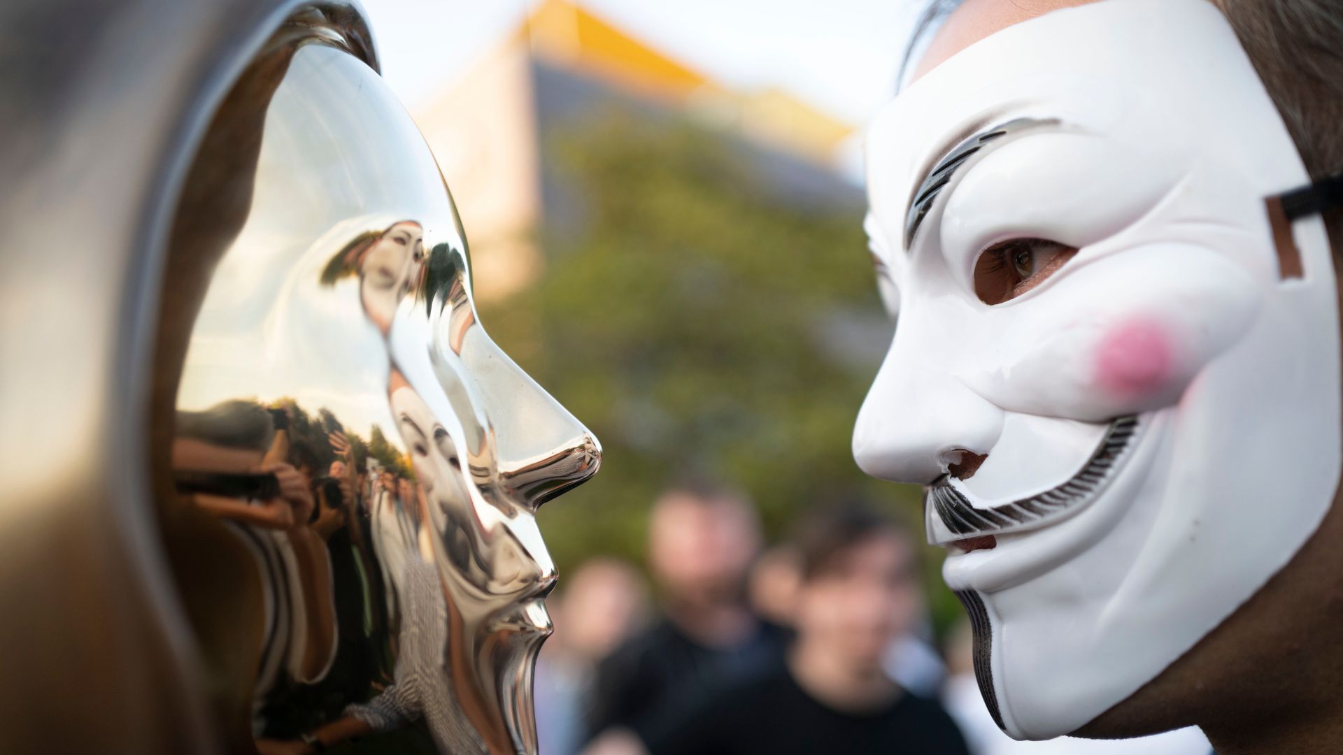 A man wearing a Guy Fawkes mask looks at a statue in honor of Satoshi Nakamoto, erected in Budapest, Hungary. /Bela Szandelszky/AP