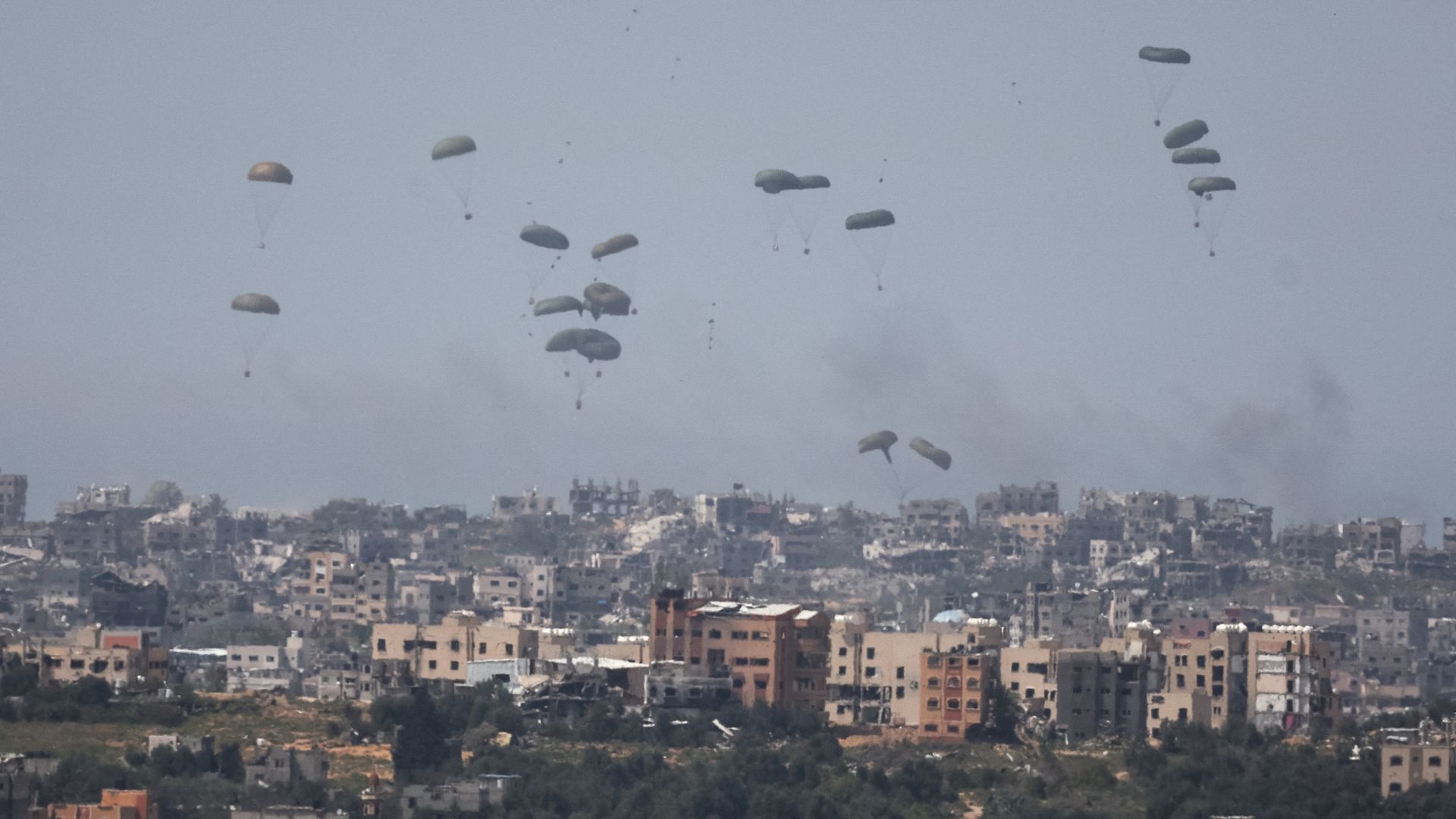 Humanitarian aid packages fall through the sky towards the Gaza Strip after being dropped from an aircraft. /Ronen Zvulun/Reuters