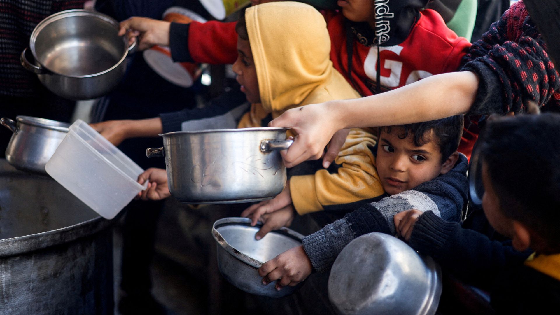 Palestinian children wait to receive food cooked by a charity kitchen amid shortages of food supplies. /Mohammed Salem/Reuters
