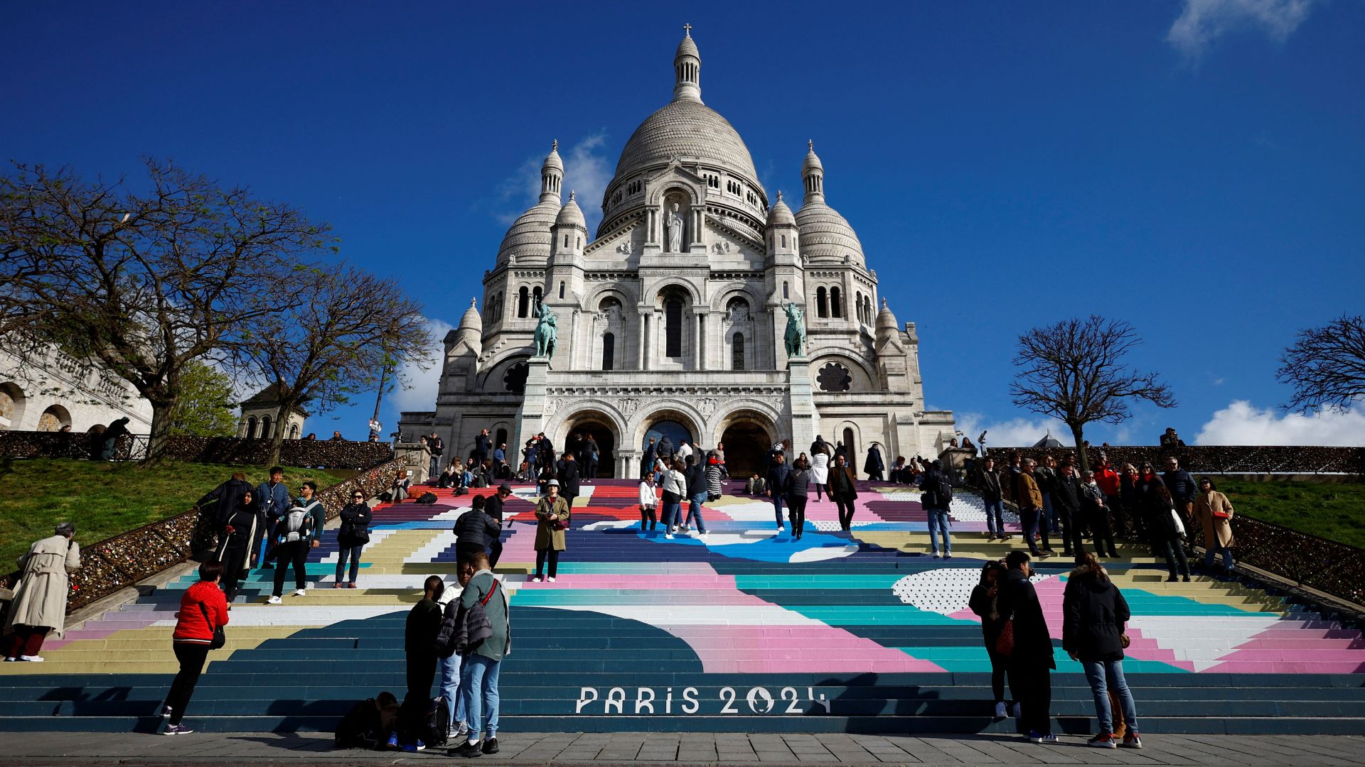 Tourists stand on the Sacre-Coeur Basilica stairs painted with the Paris 2024 Olympic and Paralympic Games design. /Sarah Meyssonnier/Reuters