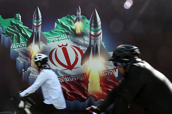 Cyclists pass a poster in Tehran. /VCG
