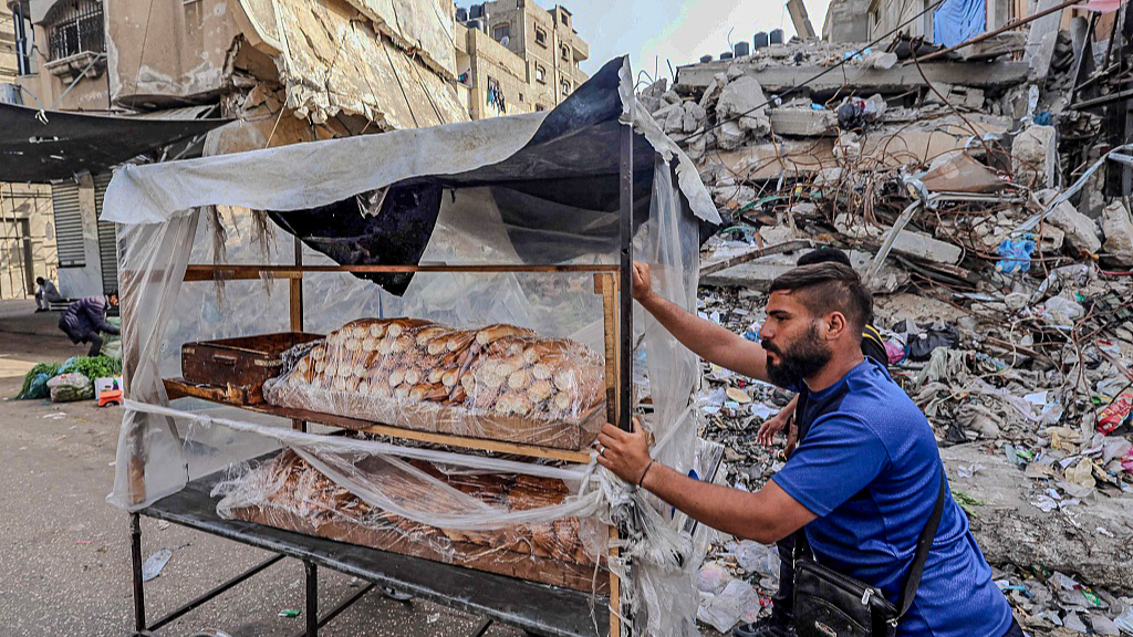 A Palestinian man sells bread amid wreckage. /Mohammed Abed/CFP