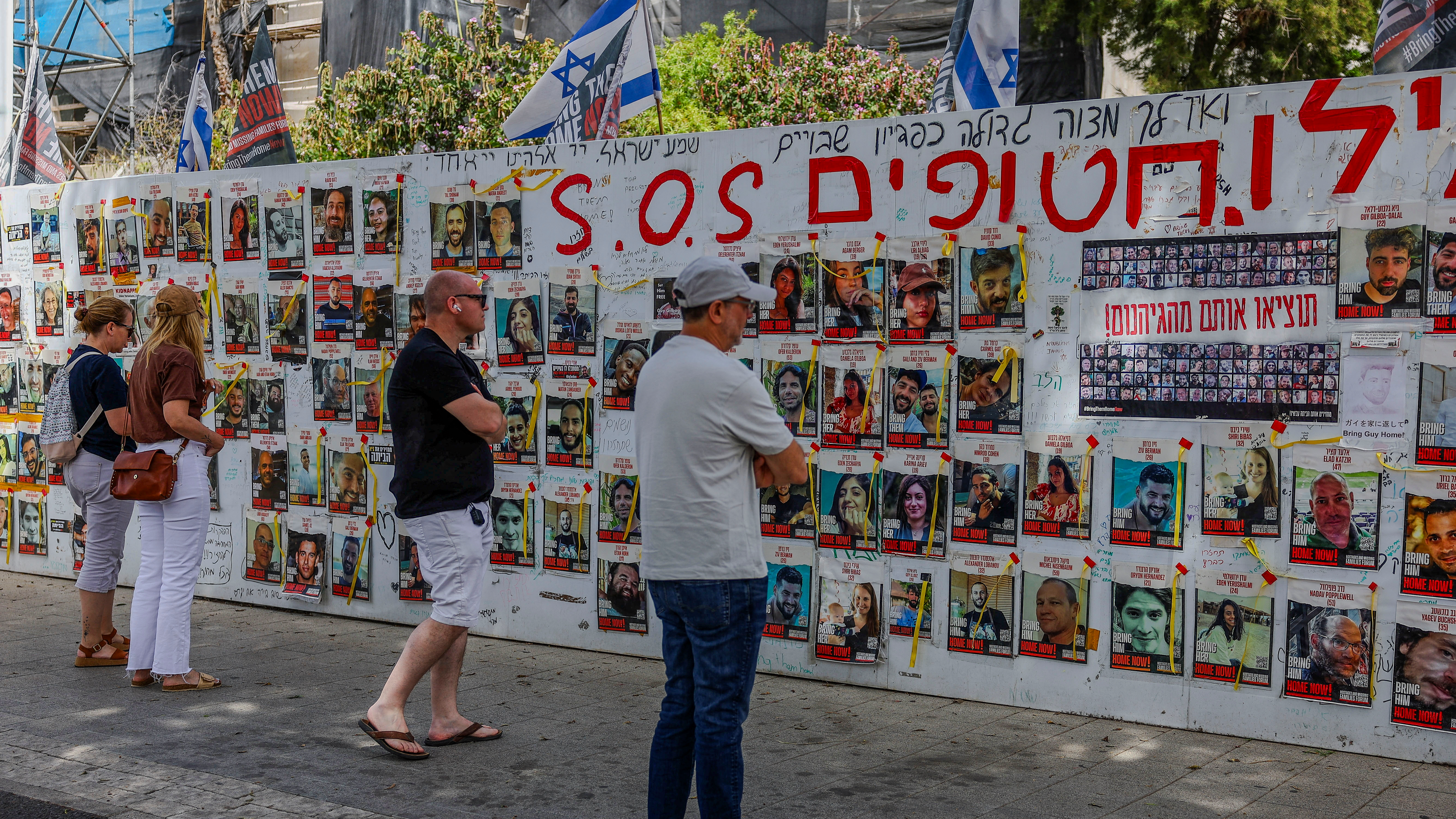 Pedestrians in Tel Aviv study a poster remembering October 7 hostages. /Hannah MvKay/Reuters