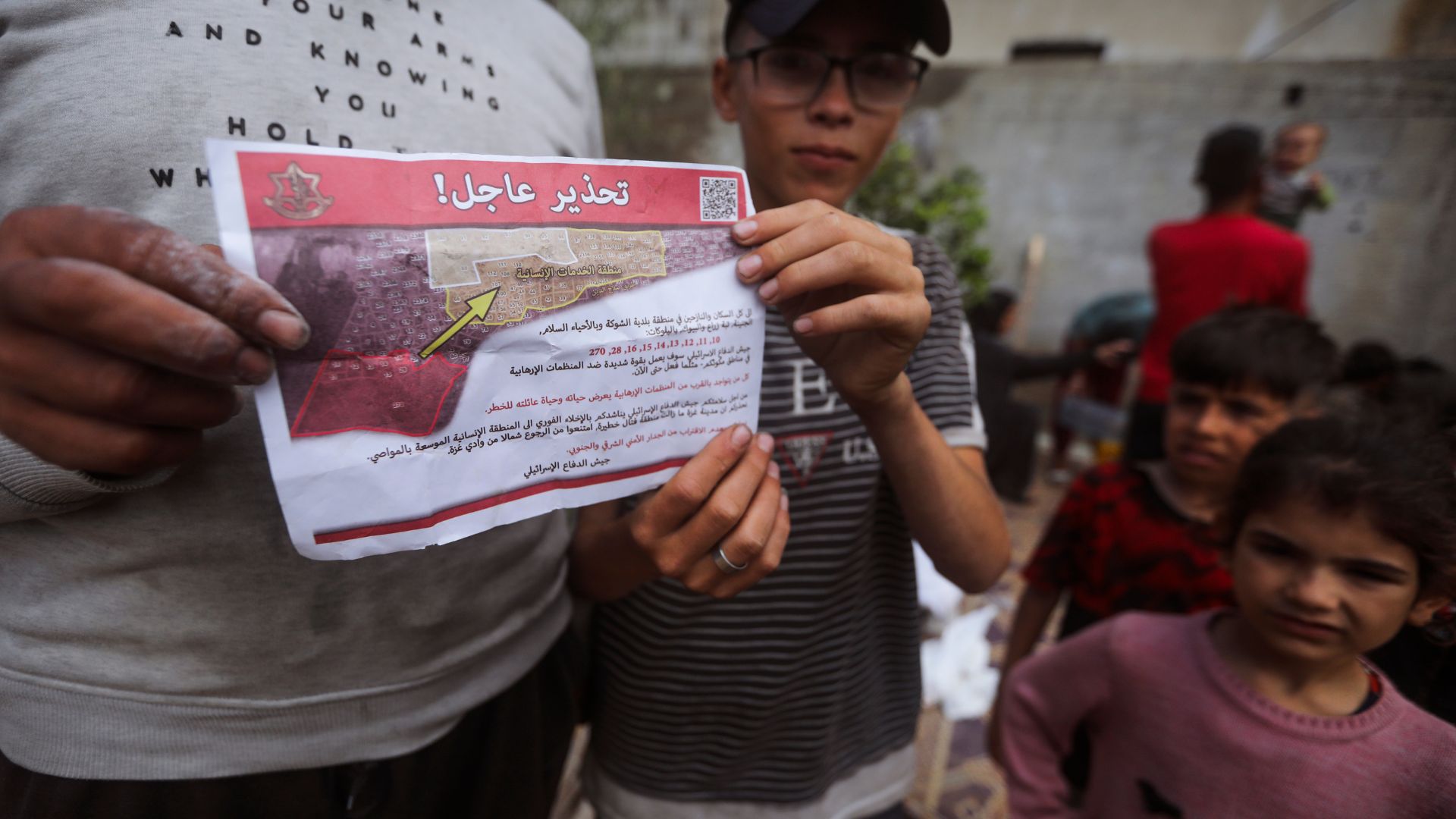 Palestinians hold leaflets dropped by Israeli planes calling on them to evacuate. /Ismael Abu Dayyah/AP