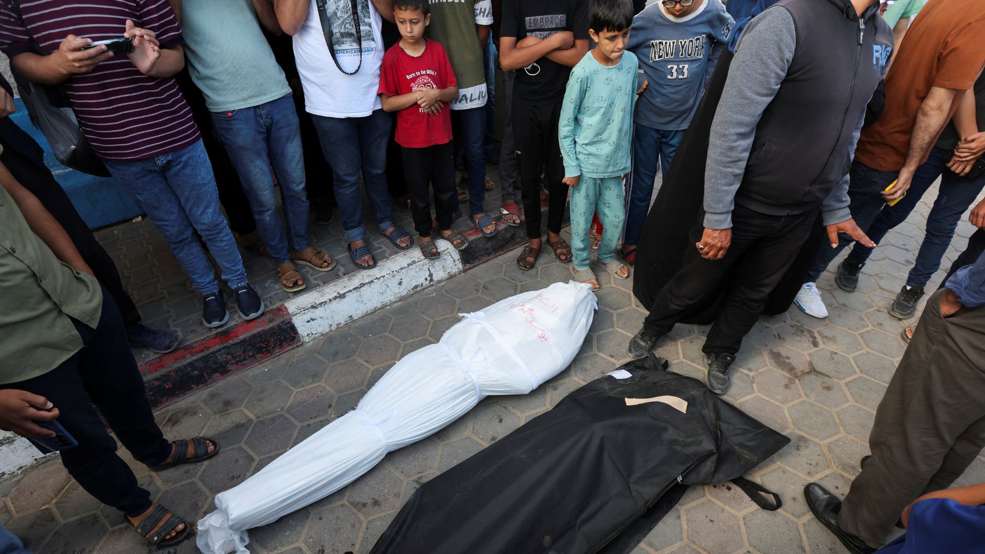 Mourners stand next to the bodies of Palestinians killed in Israeli strikes in Deir Al-Balah, in the central Gaza Strip./Ramadan Abed/Reuters