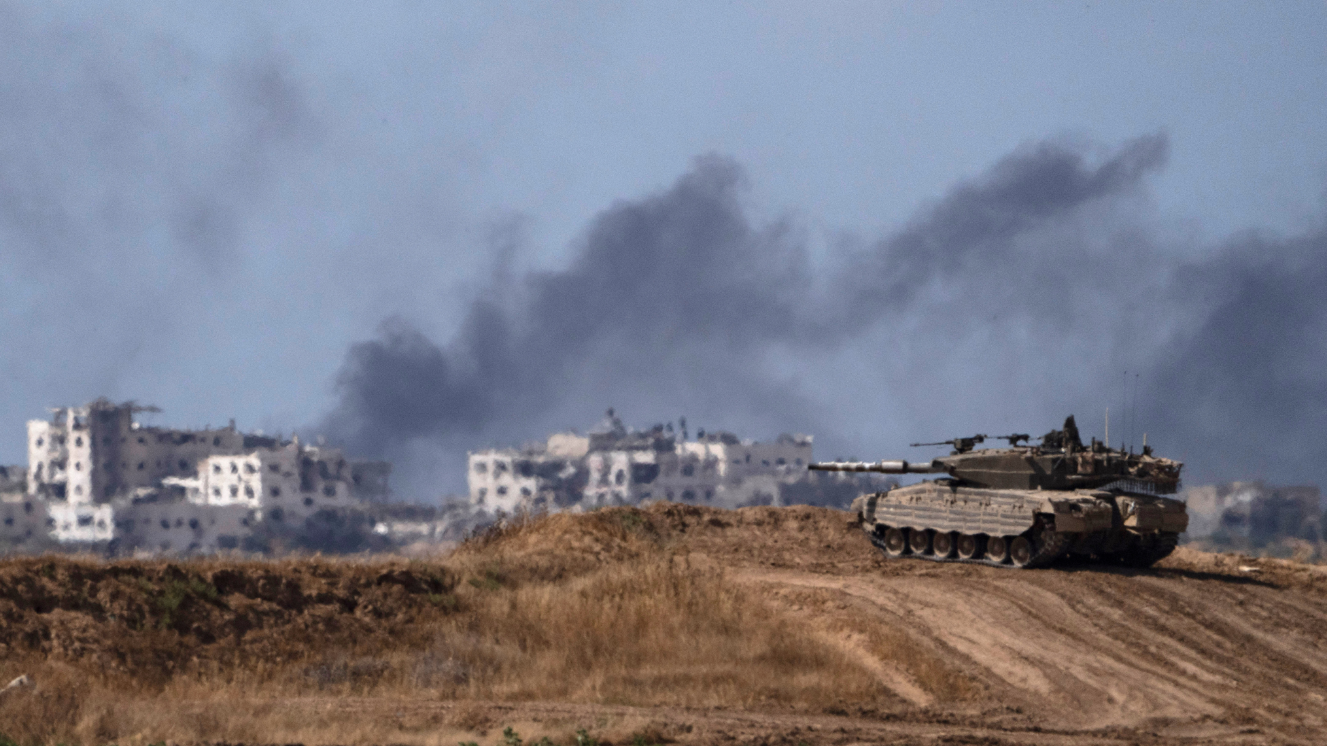 Smoke rising to the sky after an explosion in the Gaza Strip, as an Israeli tank stands near the Israel-Gaza border as seen from southern Israel. /AP /Leo Correa