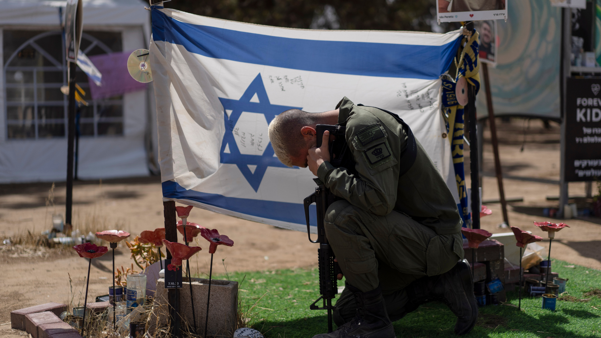 An Israeli soldier kneels next to the national flag during Israel's annual Memorial Day commemorations. /AP/Leo Correa 