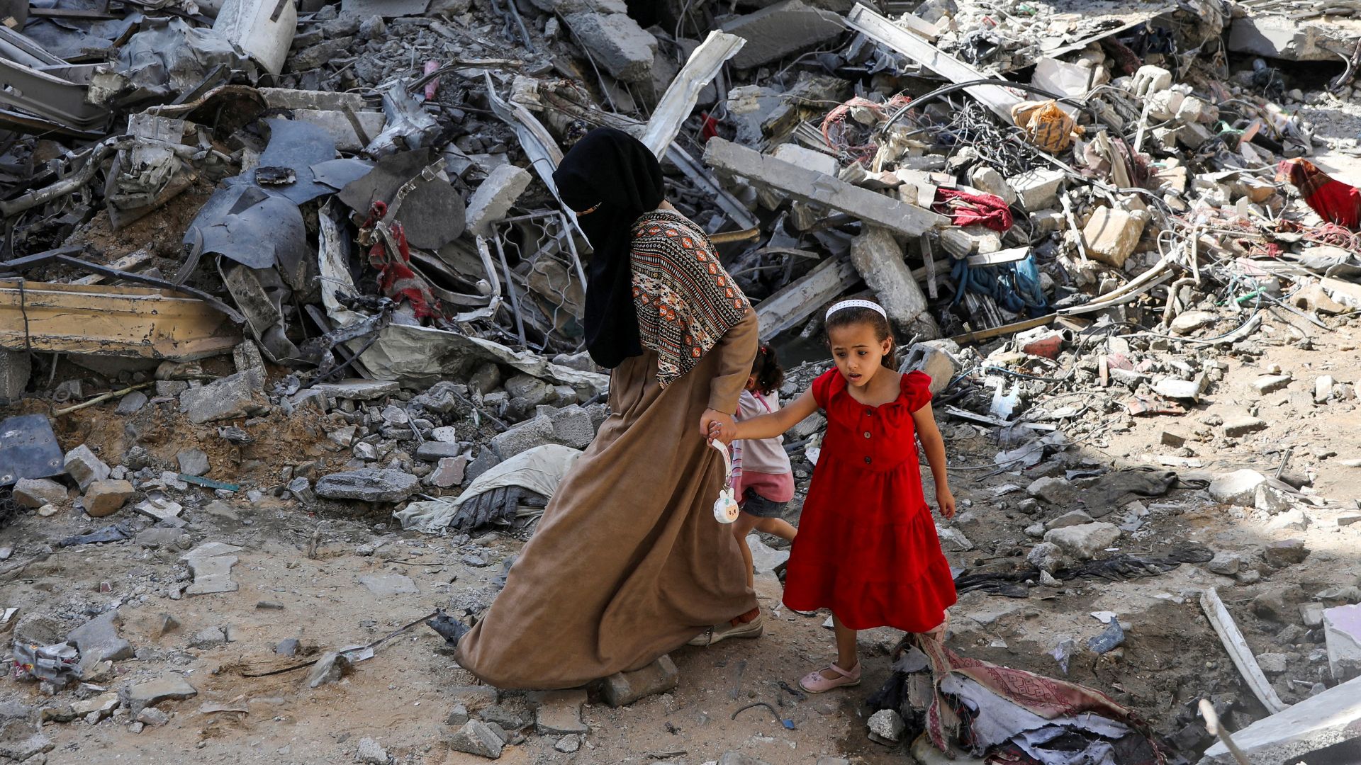 A woman and child walk among debris, aftermath of Israeli strikes at the area, where Israeli hostages were rescued on Saturday. /Abed Khaled/Reuters 