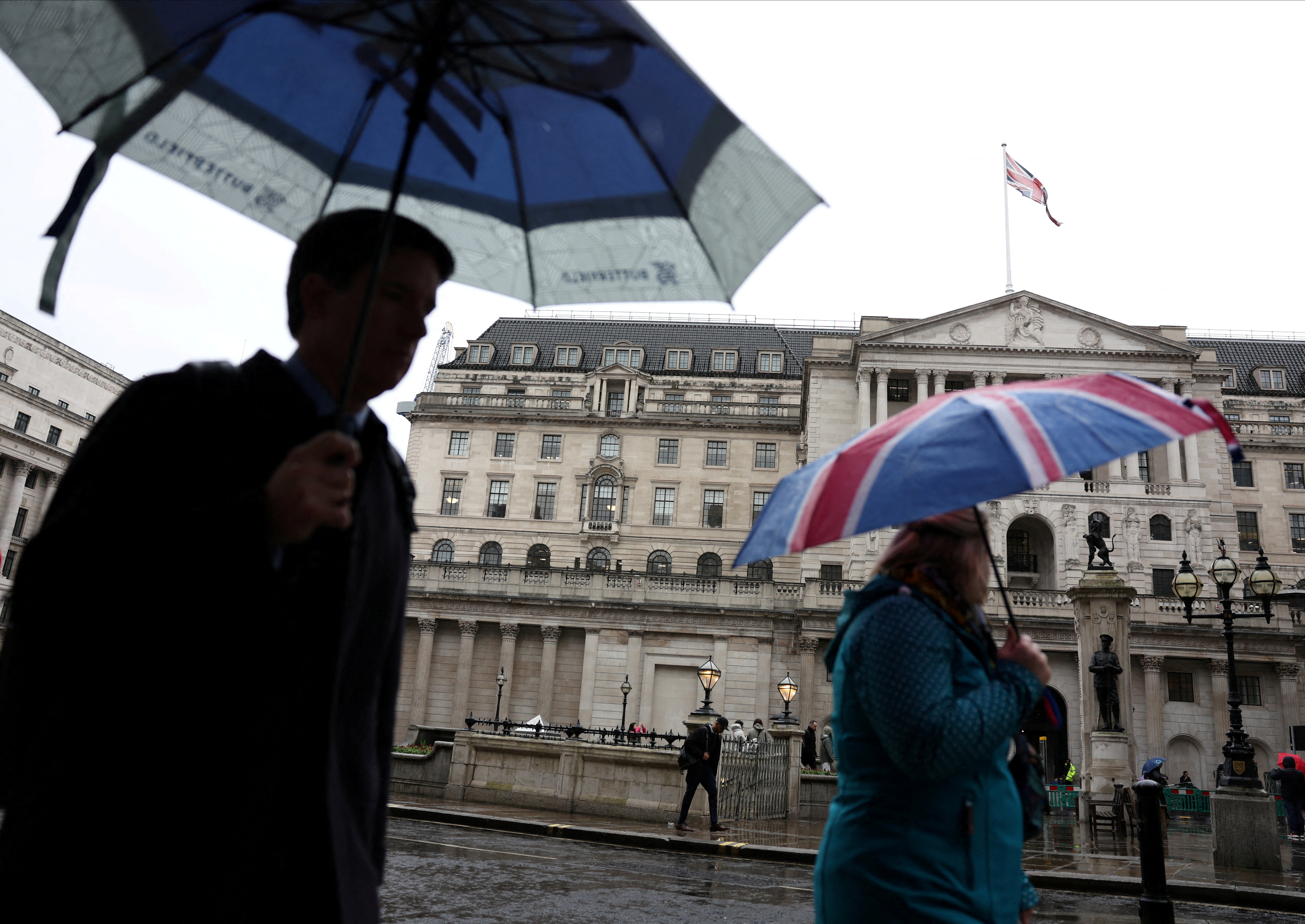 A tourist shelters from the rain under an Union Jack umbrella near the Bank of England in February. /Isabel Infantes/ReutersFile