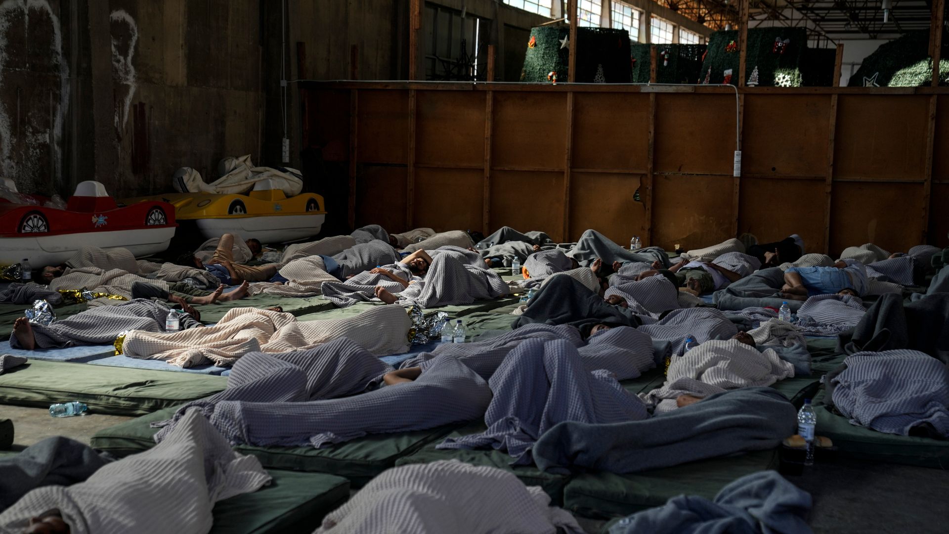 FILE- Survivors of a shipwreck sleep at a warehouse at the port in Kalamata town, about 240 kilometers (150 miles) southwest of Athens, Wednesday, June 14, 2023. /AP Photos/Thanassis Stavrakis