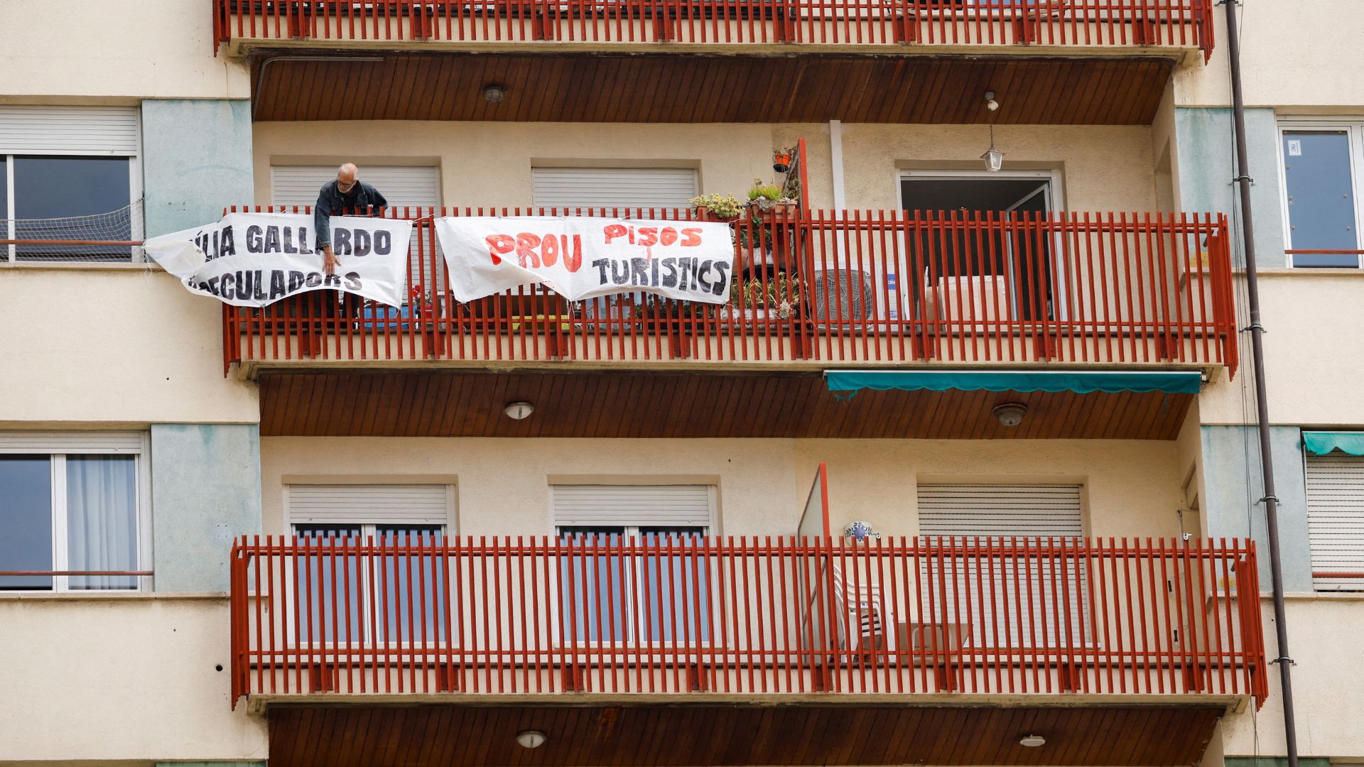 A man displays a protest banner reading 'No more tourist flats' after officials allowed a Barcelona apartment block to be used by tourists. /Albert Gea/Reuters