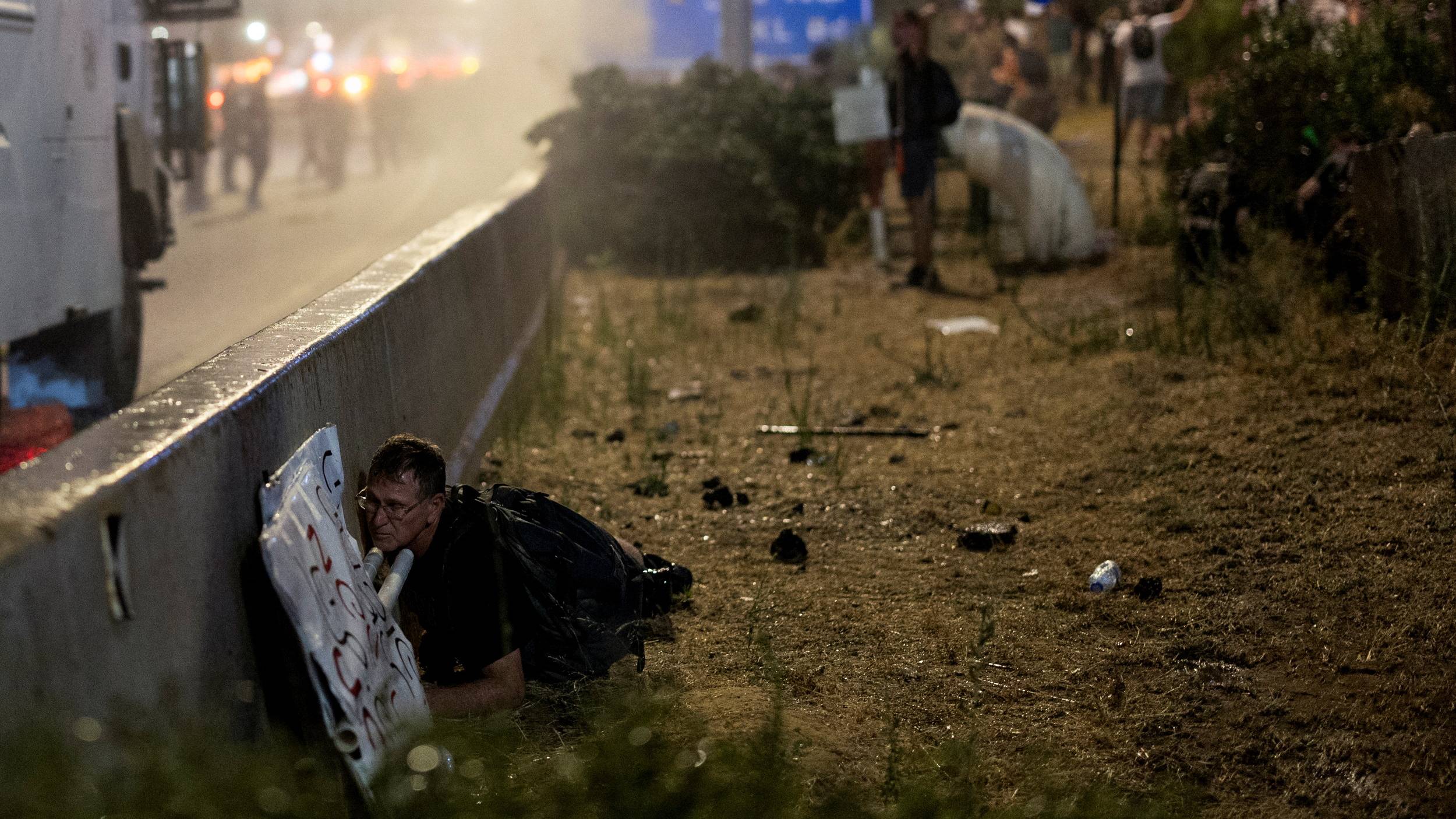 A protester takes cover as police use water cannon during a demonstration against Israeli Prime Minister Benjamin Netanyahu's government and a call for the release of hostages in Gaza in Tel Aviv. /Eloisa Lopez/Reuters