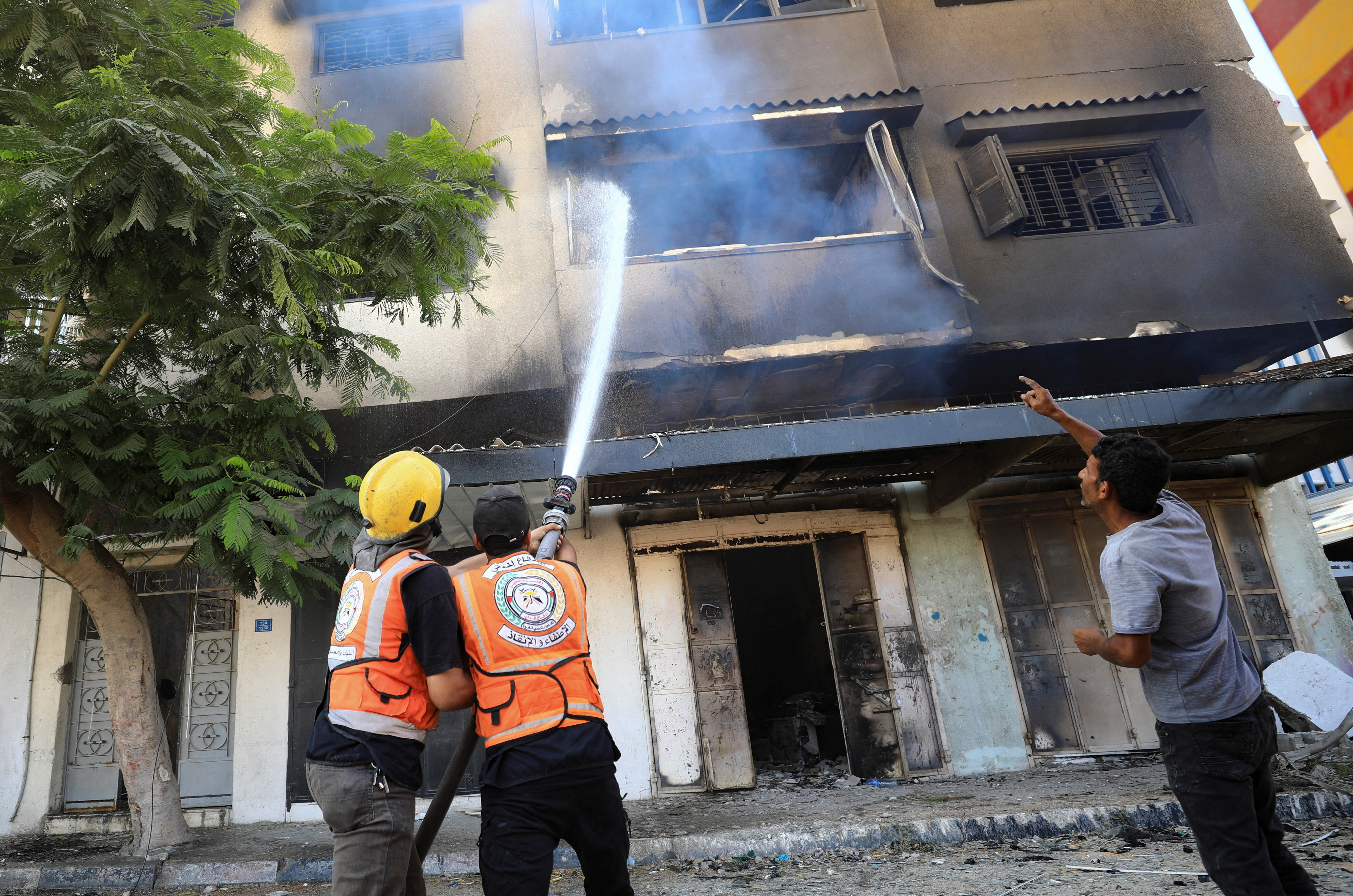 Members of the Civil Defence work to extinguish fire, after Israeli forces withdrew from a part of Gaza City, following a ground operation. /Dawoud Abu Alkas/Reuters