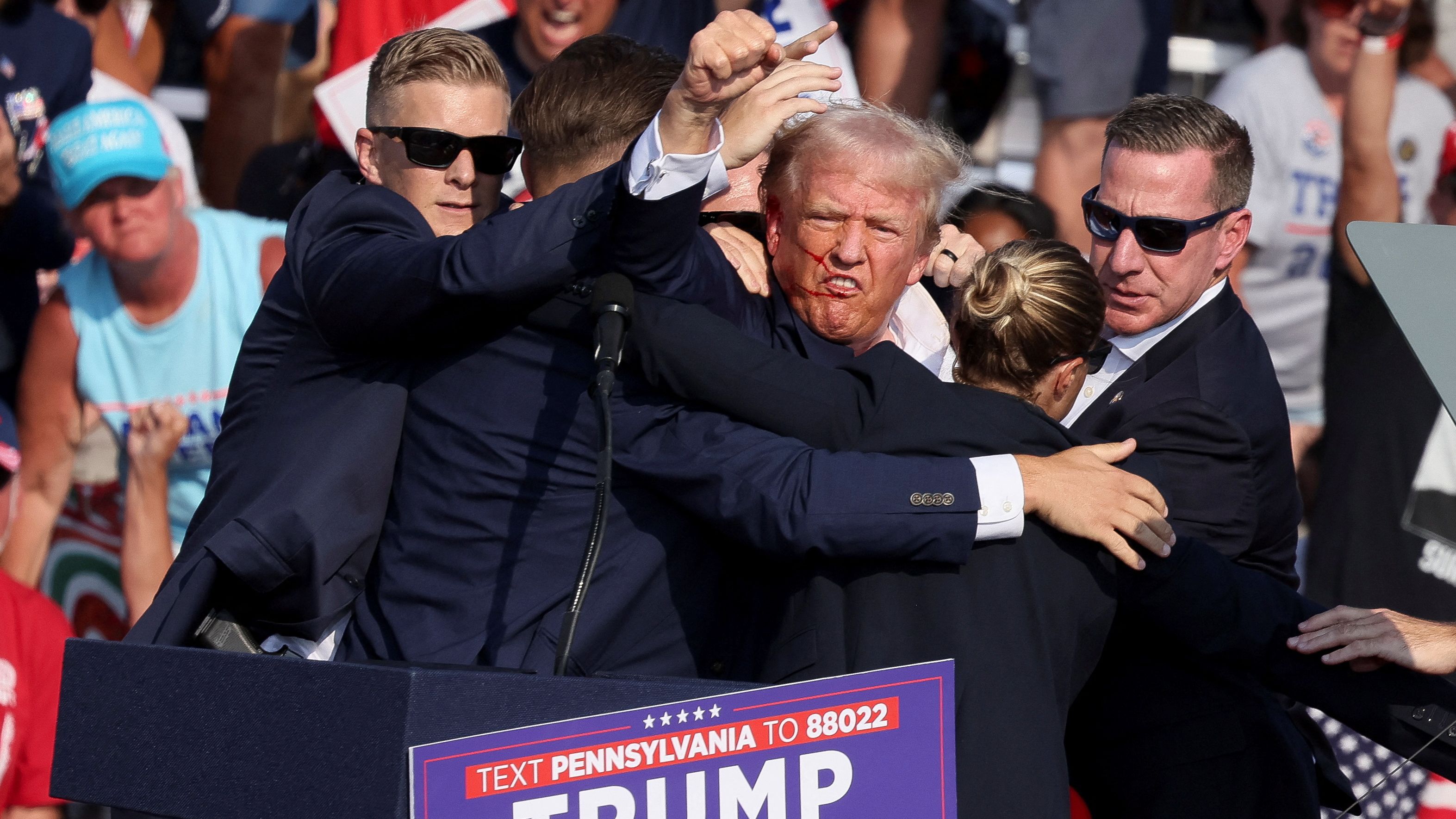 Former U.S. President Donald Trump gestures with a bloodied face after th shooting incident./ Brendan McDermid/Reuters