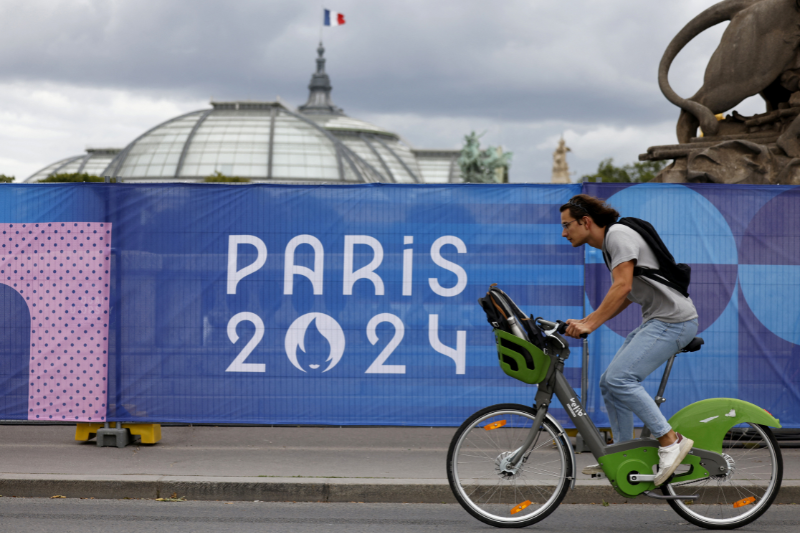 A cyclist rides a self-service Velib bike by the Alexandre III bridge Olympic site with the Grand-Palais in the background. /Ludovic Marin/AFP