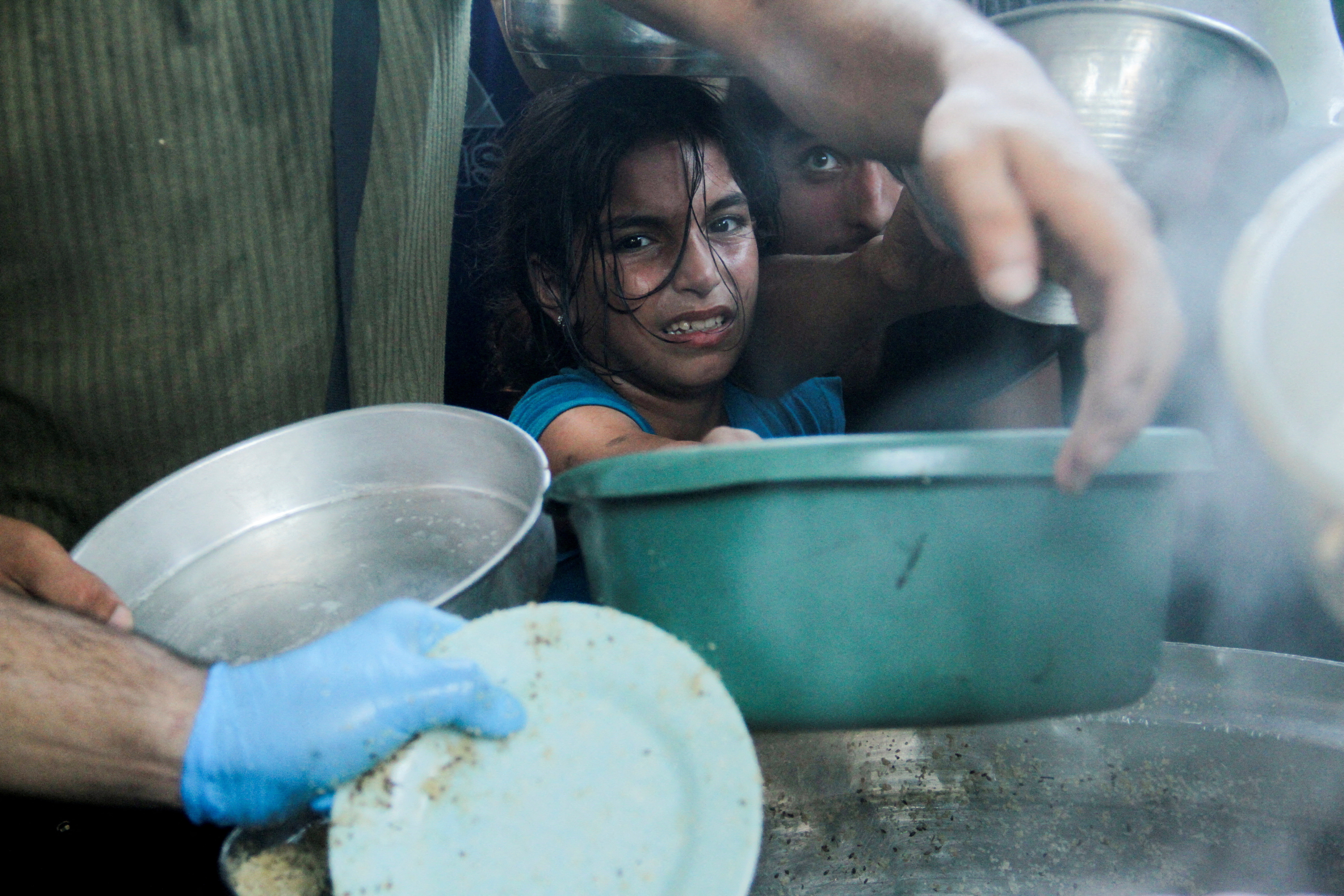 Palestinian children gather to receive food cooked by a charity kitchen in the northern Gaza Strip. /Mahmoud Issa/Reuters