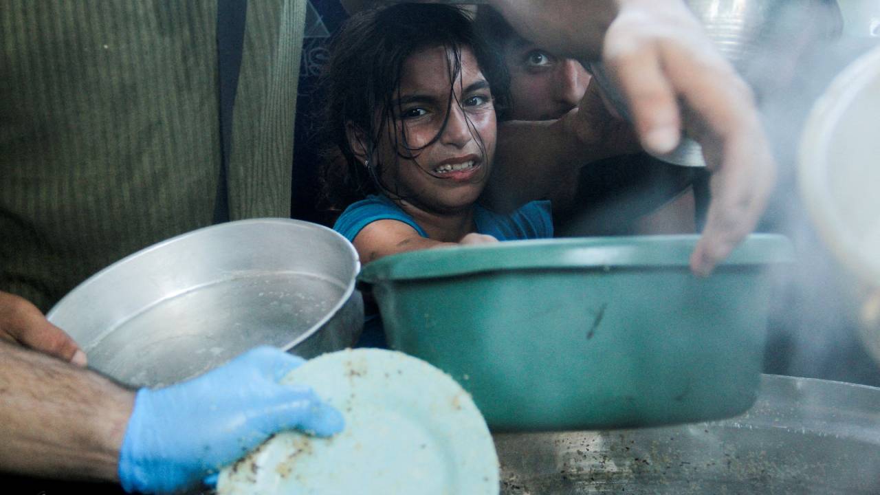 Palestinian children gather to receive food cooked by a charity kitchen in the northern Gaza Strip. /Mahmoud Issa/Reuters