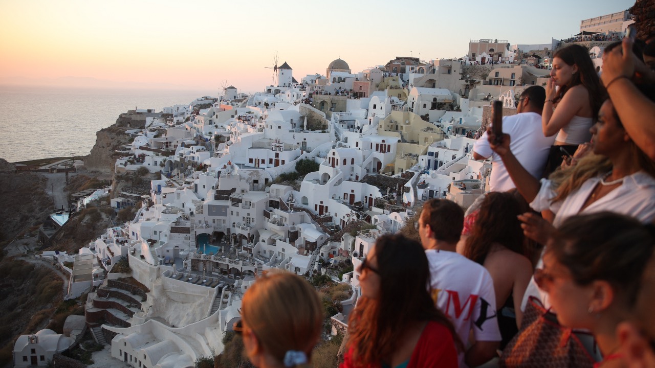 Tourists wait for the sunset in the village of Oia on the Greek island of Santorini. /Aris Oikonomou/AFP