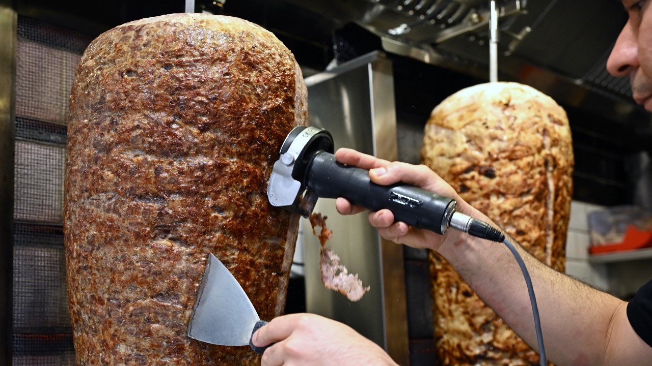 An employee scapes meat from a kebab skewer in a snack bar in the city center of Dortmund, western Germany. /Ina Fassbender/AFP