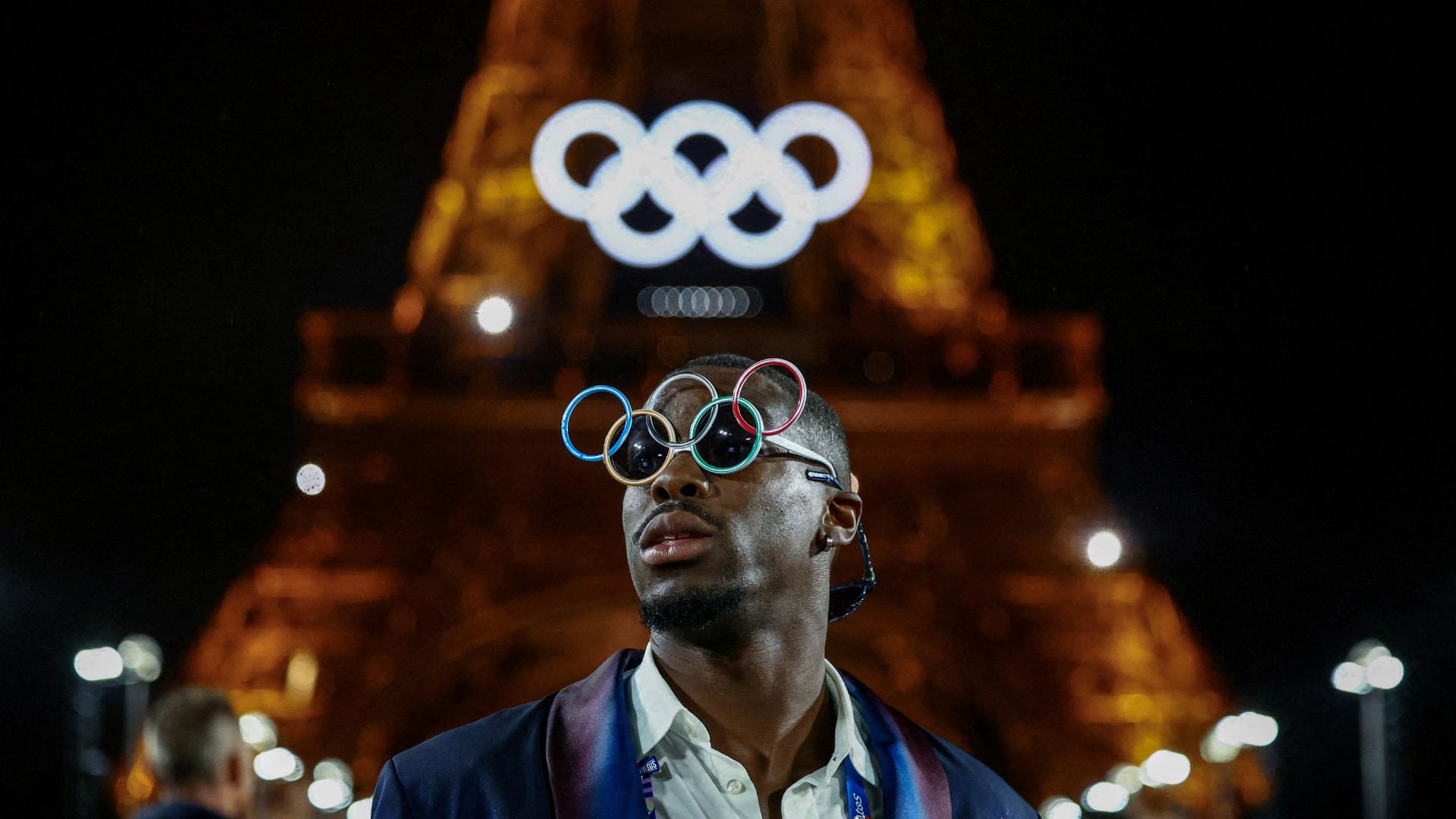 Handball player Dylan Nahi of France wears glasses with the Olympic rings near the Eiffel Tower, during the opening ceremony of the Paris 2024 Olympics. /Edgar Su/Reuters