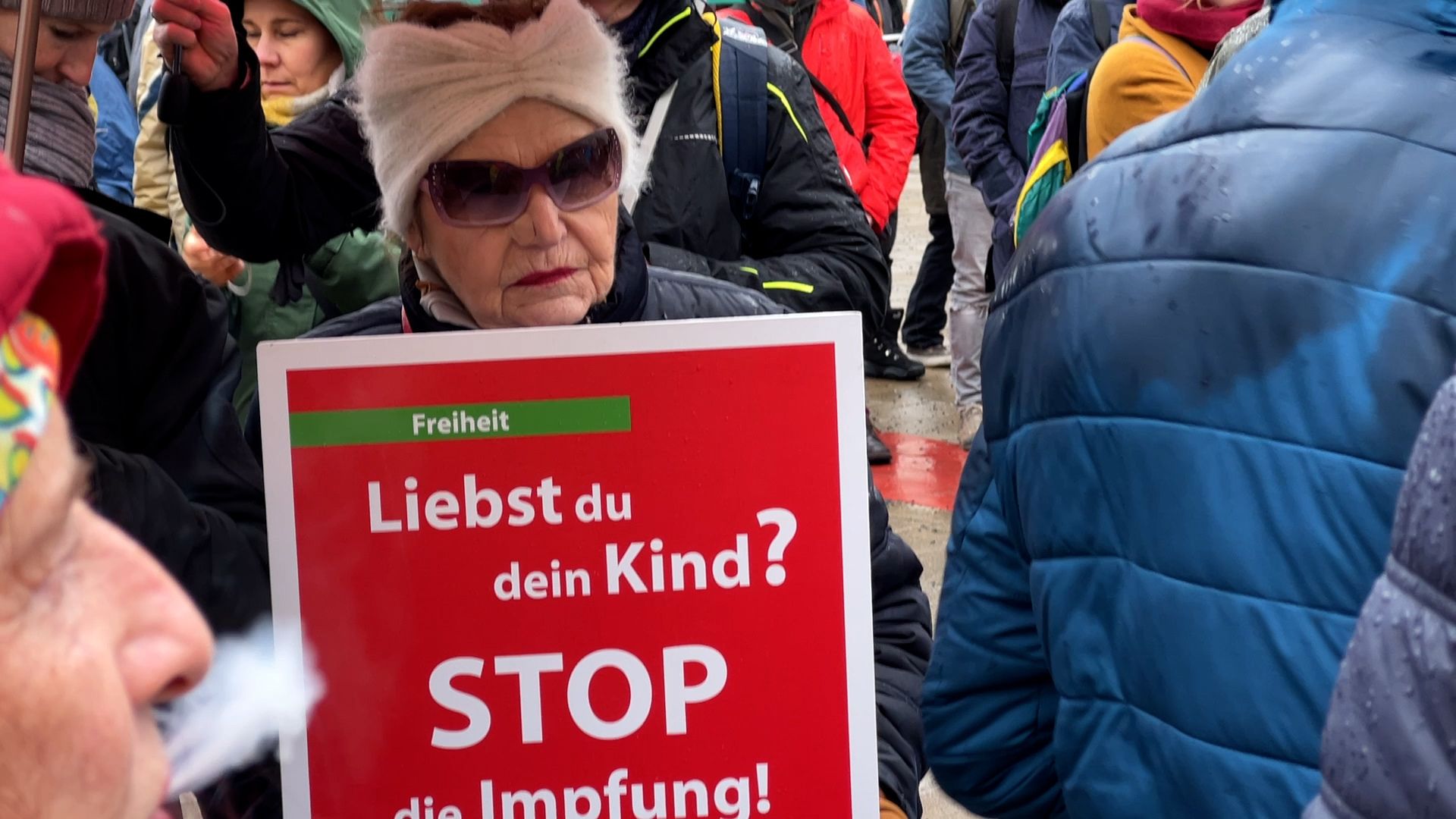 Anti-Covid measures protester in Vienna holding a sign saying_'Do you love your child? Stop vaccinating.' /Johannes Pleschberger/CGTN