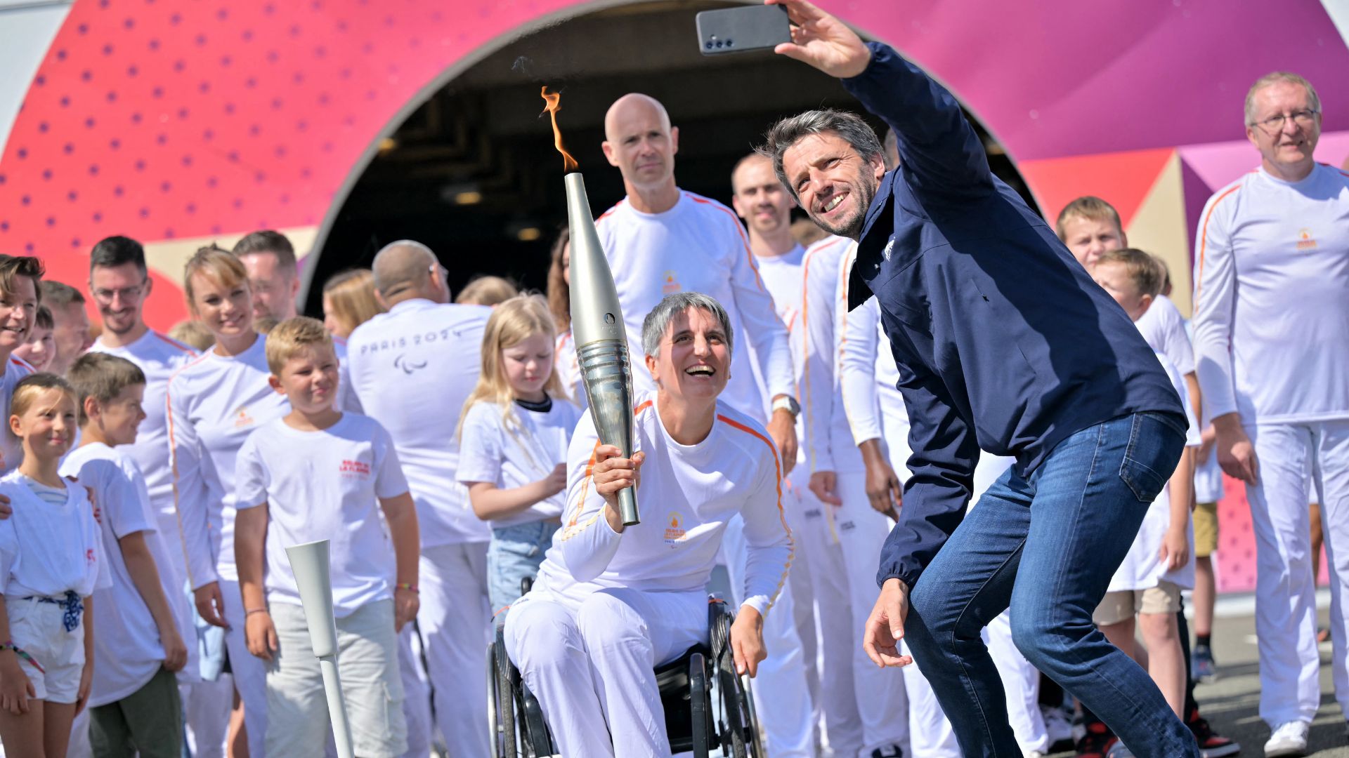 Paris 2024 president Tony Estanguet takes a selfie with former international wheelchair fencer Emmanuelle Assmann after the arrival of the Paralympics flame through the Channel Tunnel. /Lou Benoist/AFP