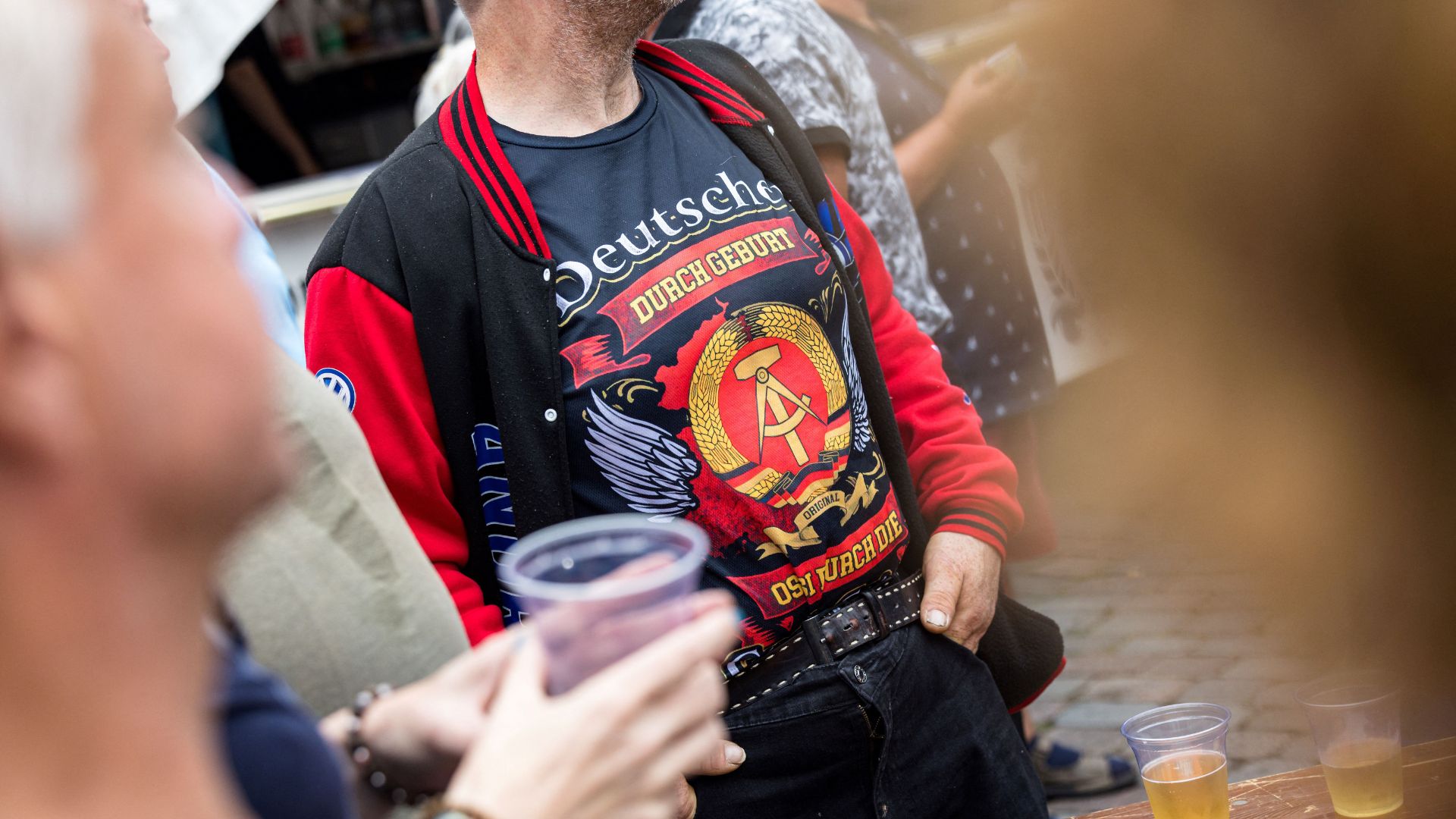 An AfD event attendant wears a T-shirt saying 'German by birth' with the former German Democratic Republic emblem in Apolda, Thuringia. /Jens Schlueter/AFP