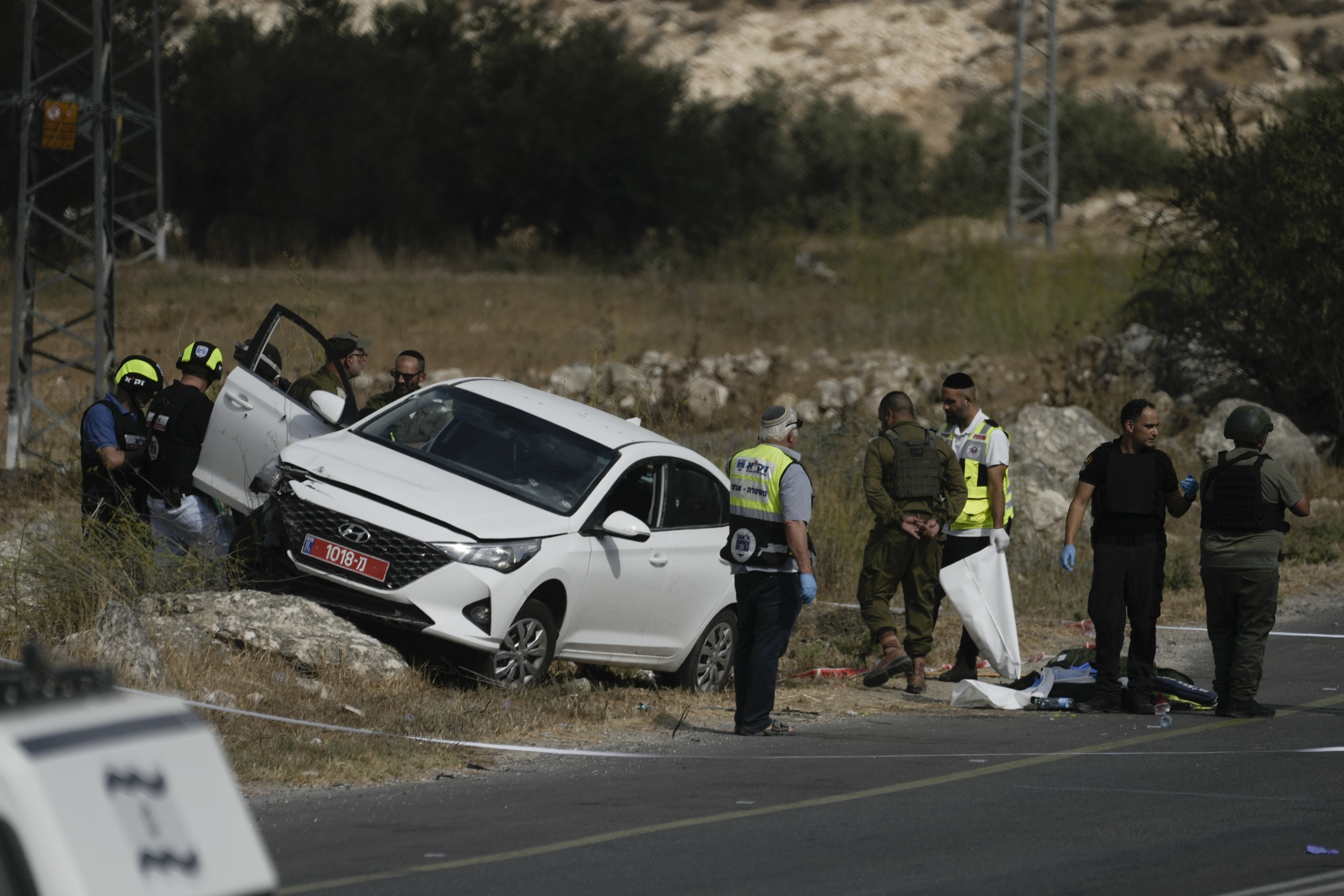 Israeli security forces and rescue services check the scene of a shooting attack in the West Bank city of Tarkumiya. /Mahmoud Illean/AP