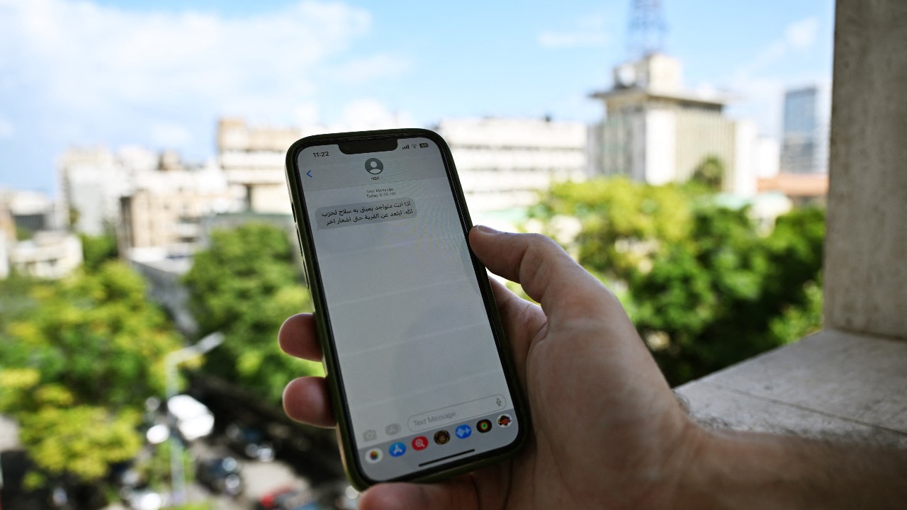 A Lebanese man checks a message received on his mobile phone in Beirut, calling people to evacuate areas where Hezbollah hides weapons. /Joseph Eid/AFP