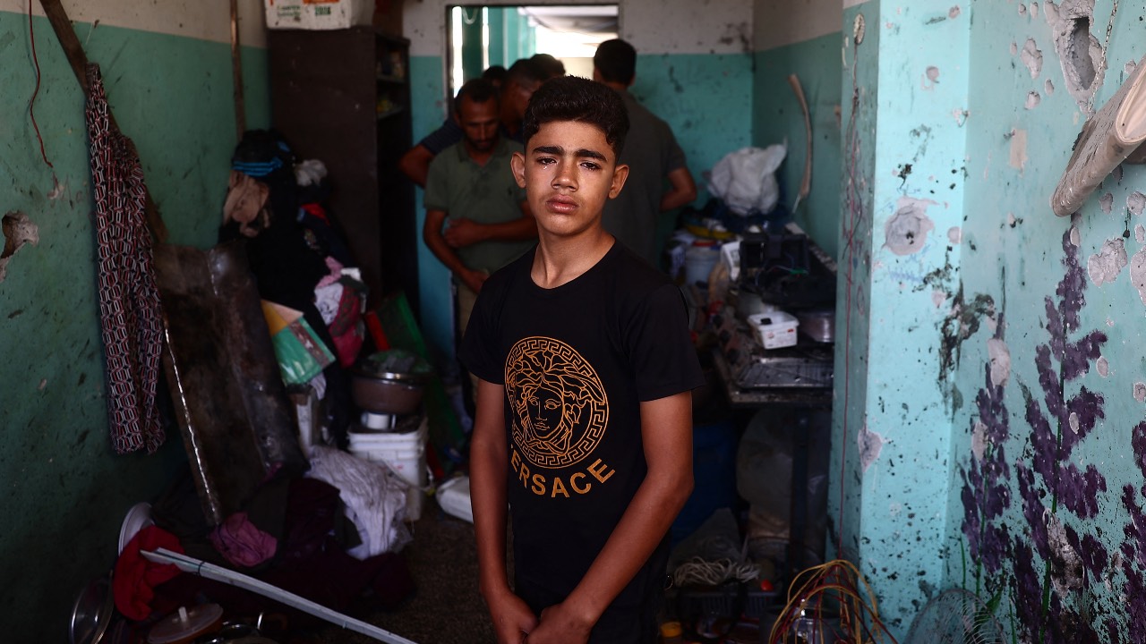 A Palestinian boy weeps as he checks the damage at a room at a school sheltering displaced people after an Israeli air strike hit the site, in Nuseirat in the central Gaza Strip. /Eyad Baba/AFP