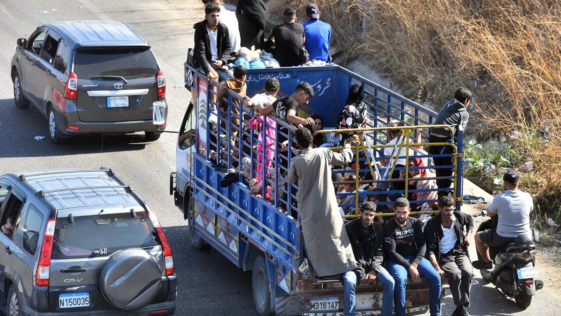 People sit with their belongings in the back of a truck as they arrive in the coastal town of Naameh, south of Lebanon's capital Beirut. /Fadel Itani/ AFP