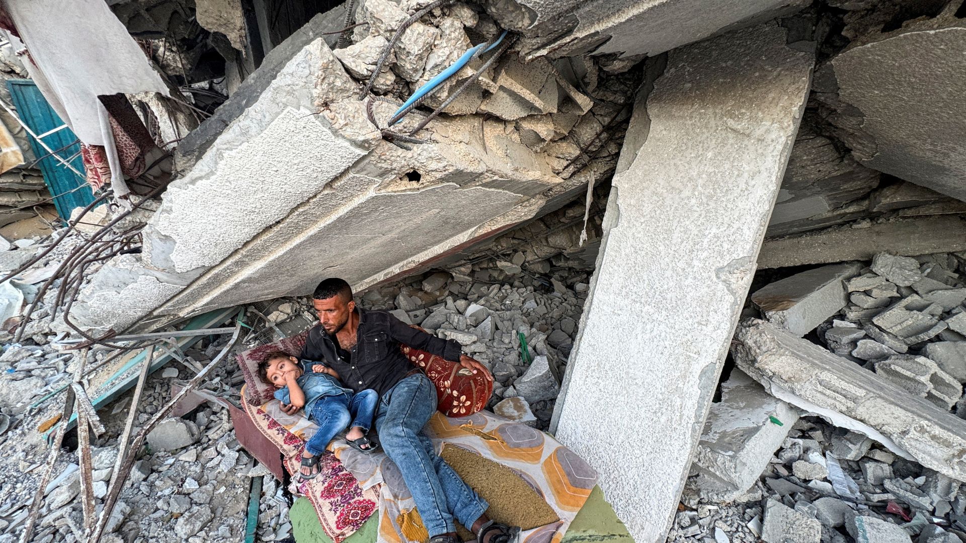 Palestinians rest under the rubble of a house in Khan Younis in the southern Gaza Strip. /Mohammed Salem/Reuters