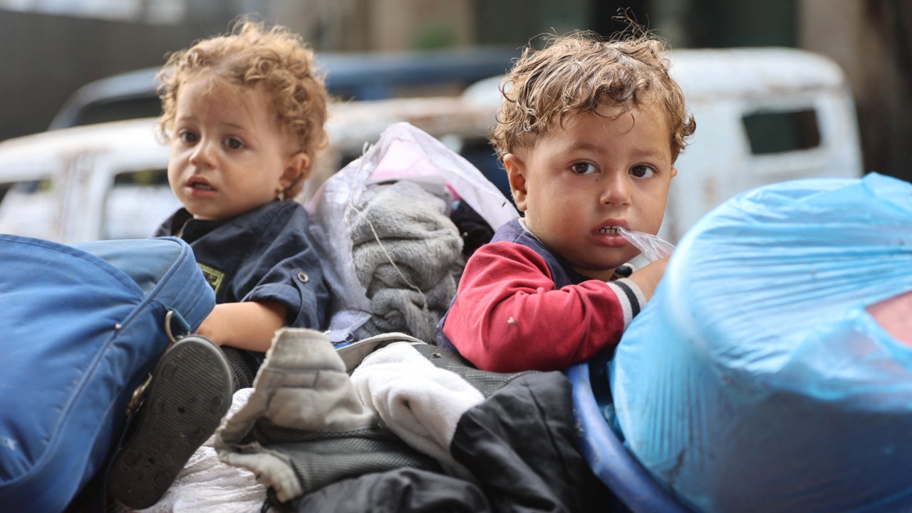 Palestinian children sit with their belongings in the back of a makeshift trolley as they arrive in Gaza City after evacuating their homes in the Jabalia area after the Israeli army ordered people to evacuate the area north of Gaza. /Omar al-Qattaa/AFP