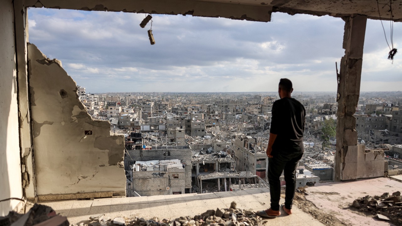 A man standing atop a heavily damaged building looks at other destroyed buildings in Khan Yunis in the southern Gaza Strip. /Bashar Taleb/AFP